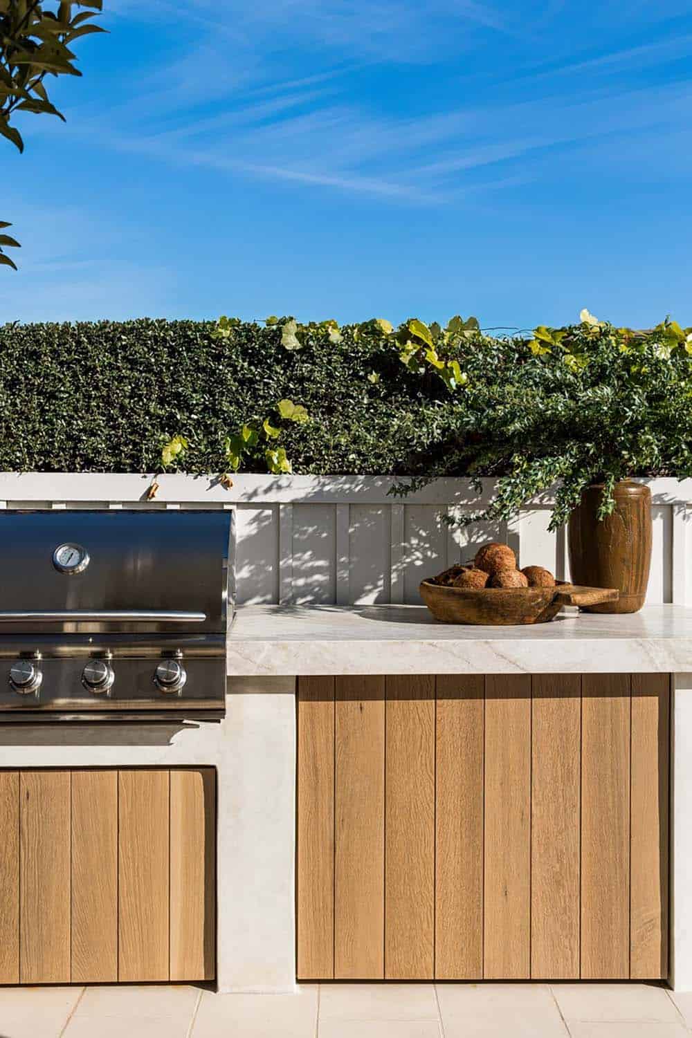 Outdoor kitchen with stainless grill and wood cabinet paneling