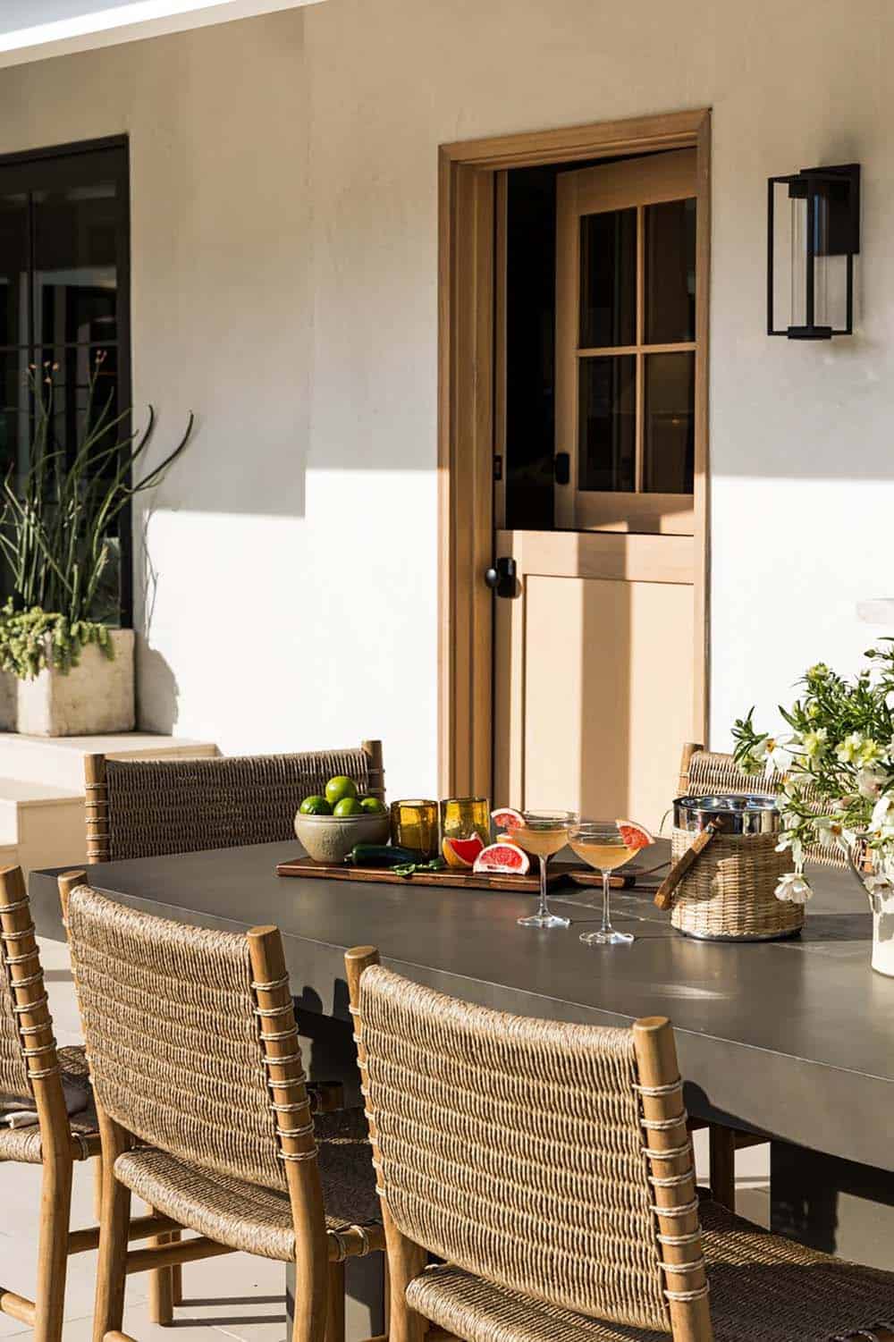 Outdoor dining table set with woven chairs and citrus garnish