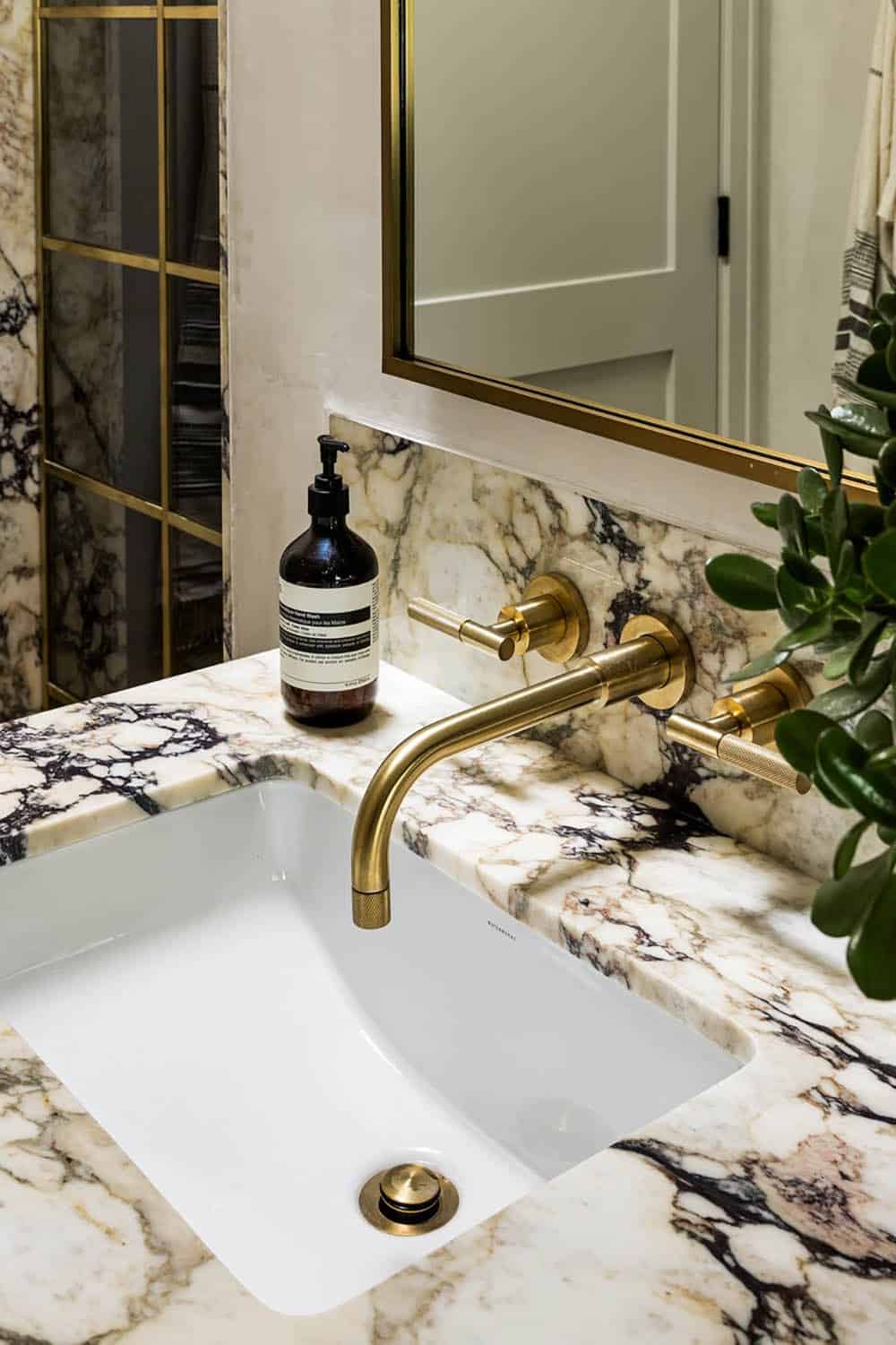Marble bathroom sink with brass wall-mounted faucet and fixtures