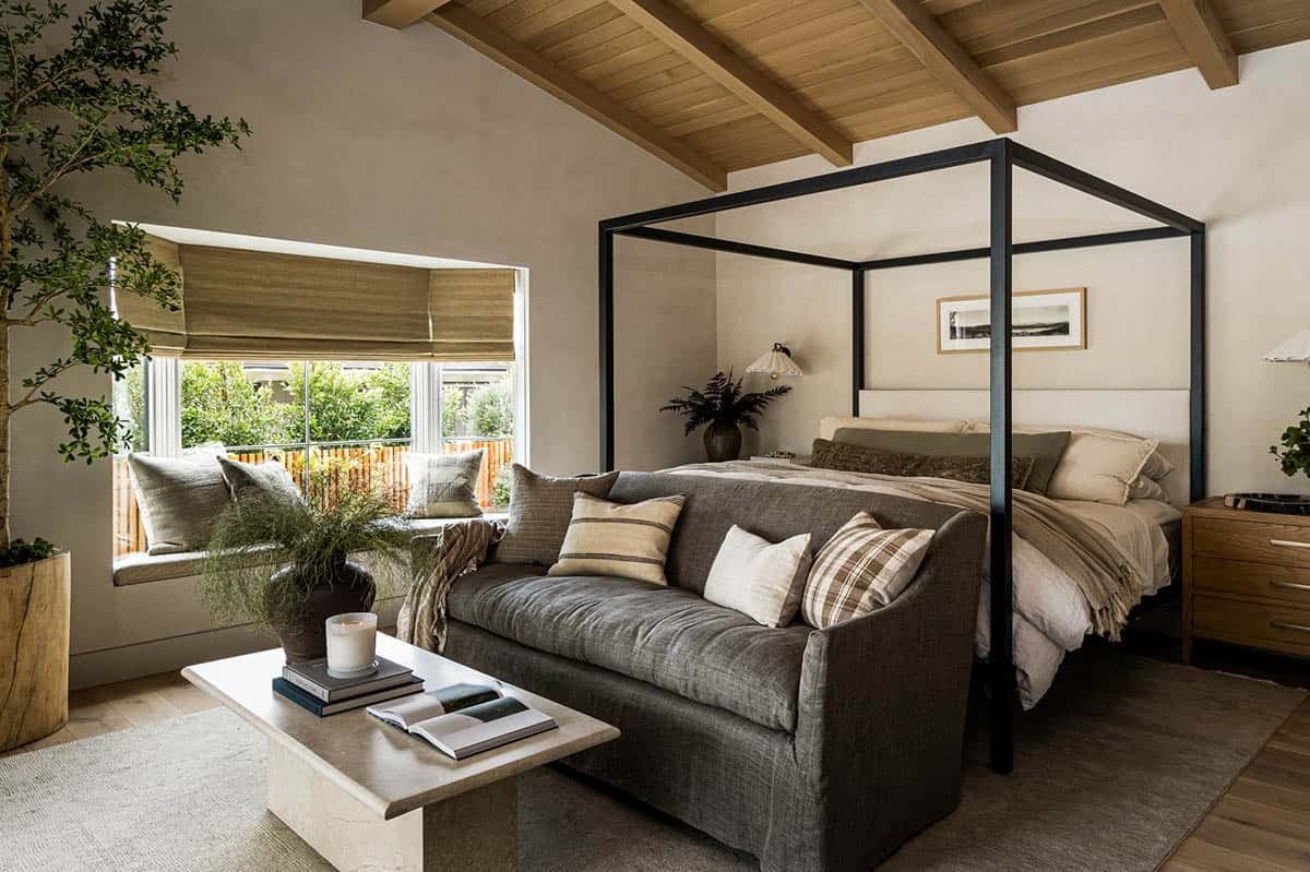 Canopy bed with linen sofa in wood-beamed vaulted bedroom