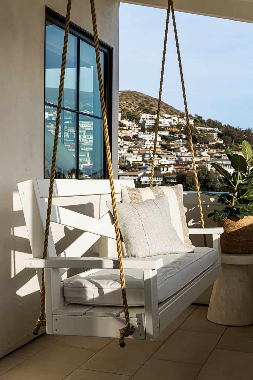 White rope porch swing overlooking hillside coastal neighborhood view