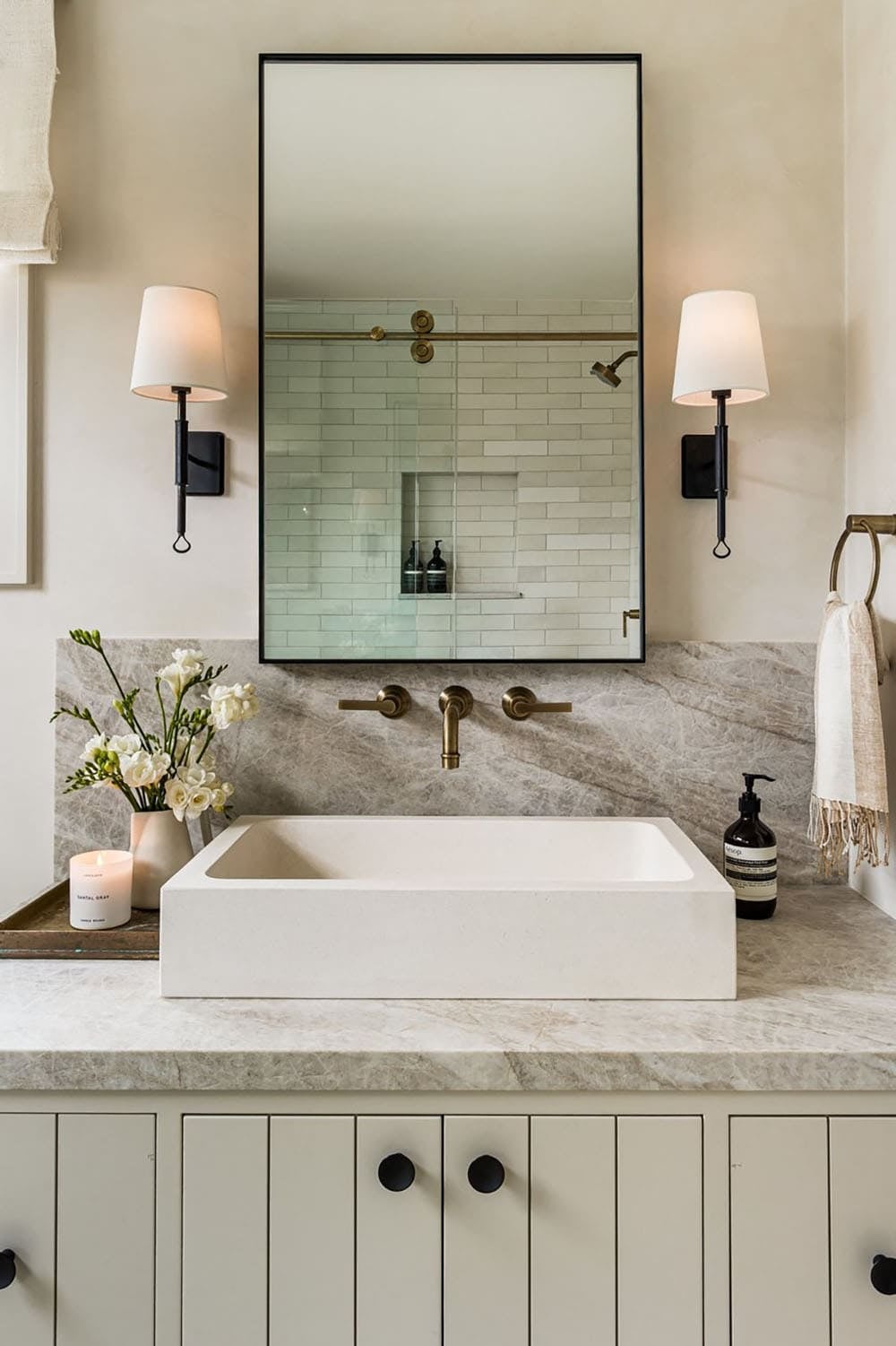 Floating vessel sink with marble backsplash and black sconces