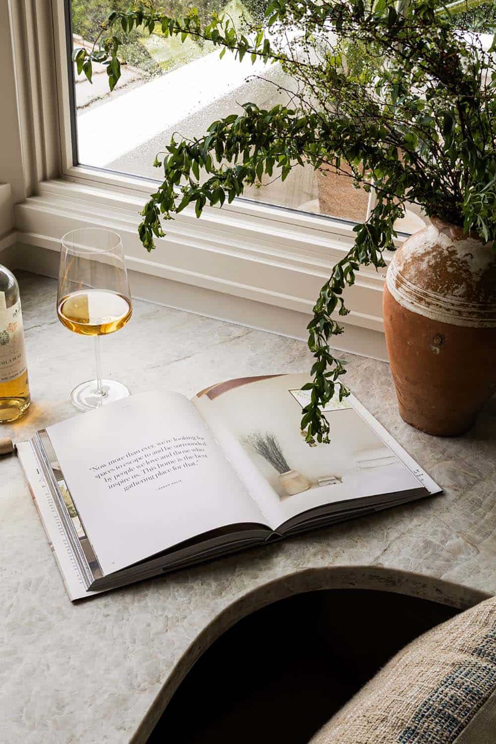 Marble countertop nook with wine glass and open coffee table book