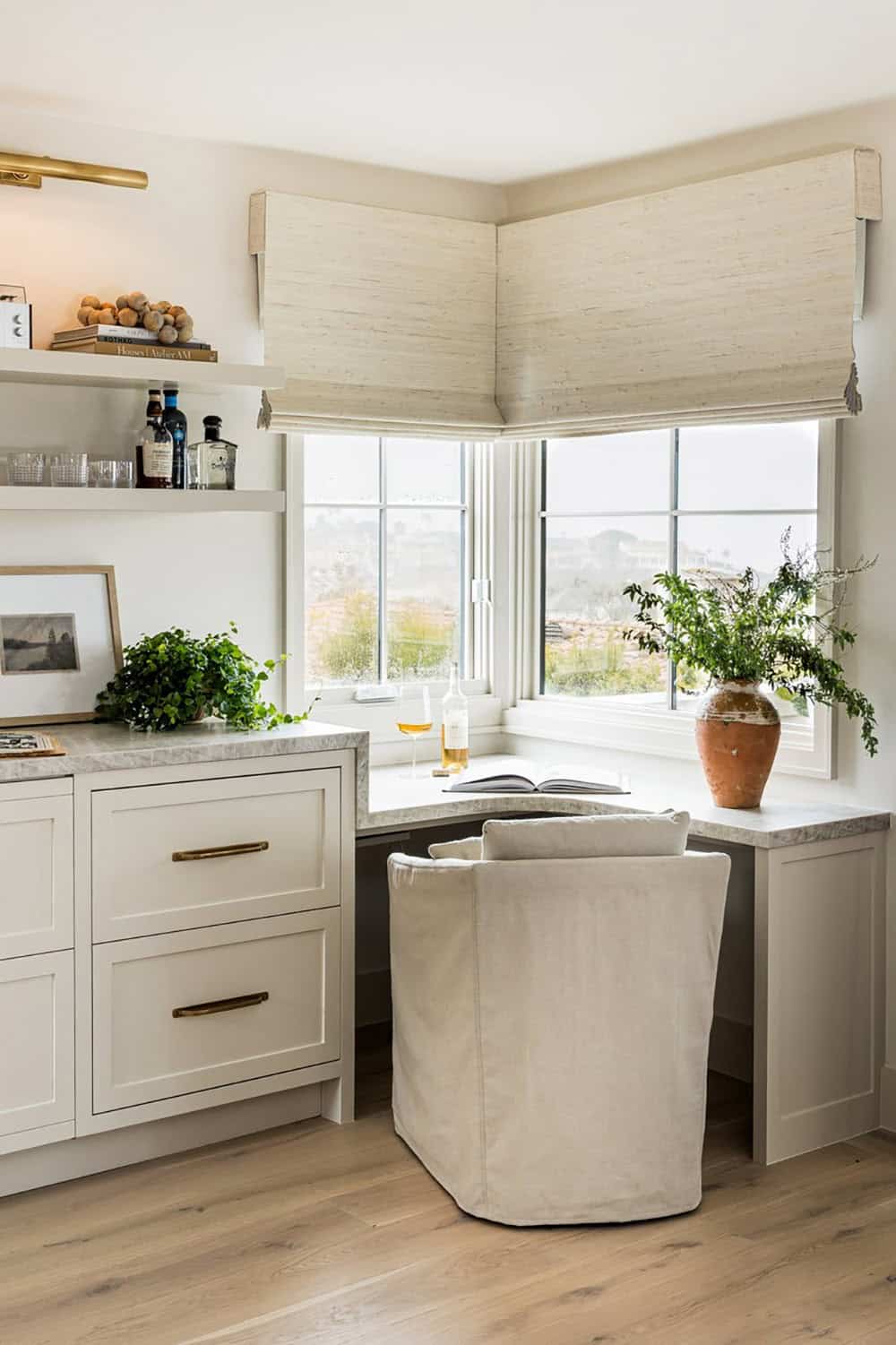 Corner window nook with built-in desk and slipcovered chair