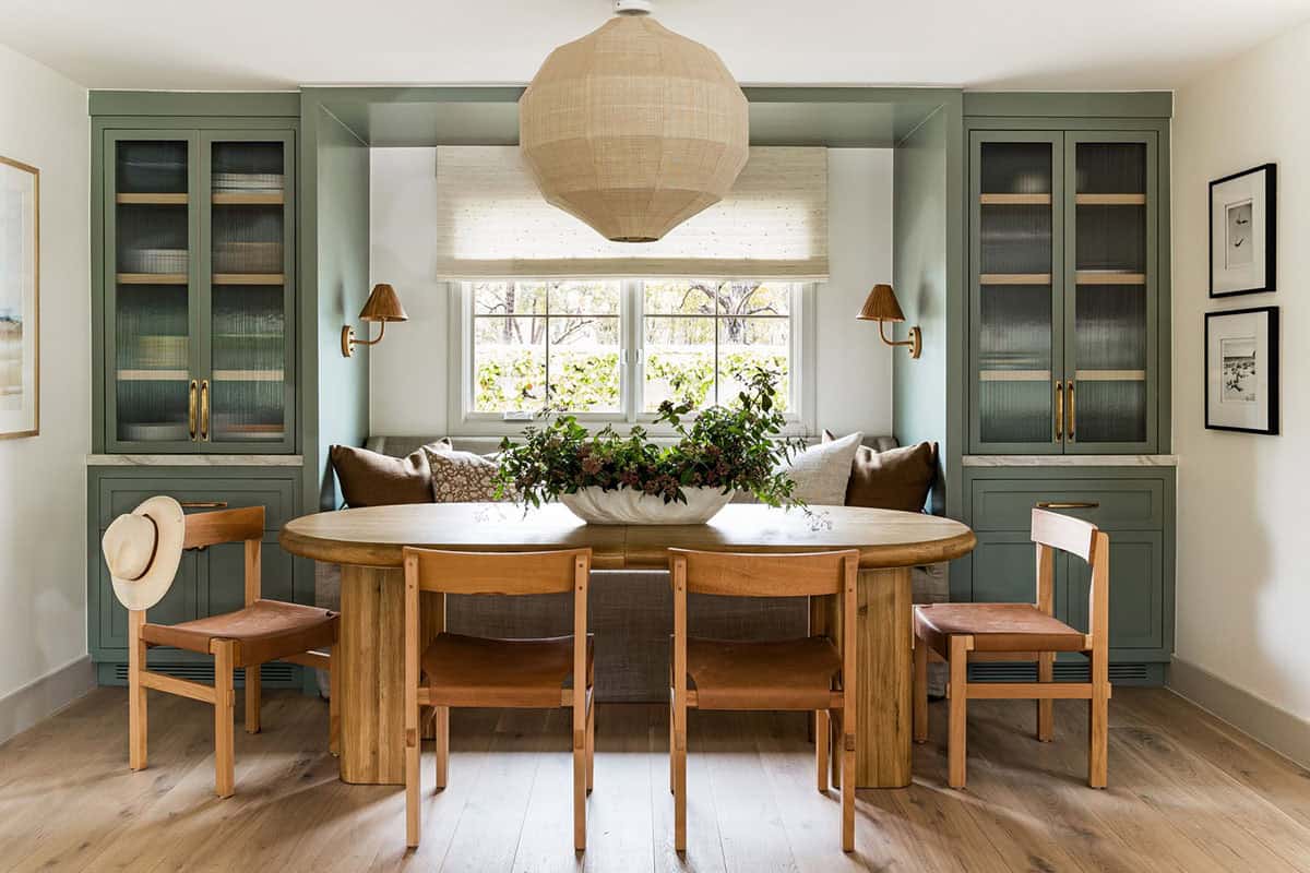 Green built-in dining nook with round table and leather chairs