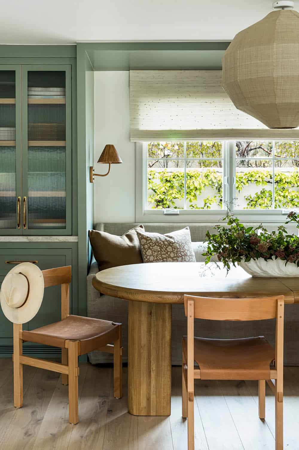 Green dining banquette with woven pendant and leather chairs
