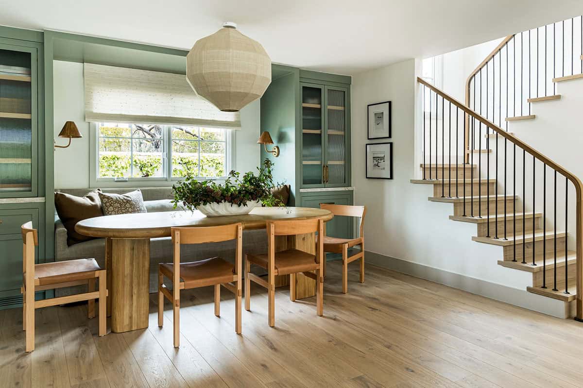 Dining nook with woven pendant light beside curved staircase