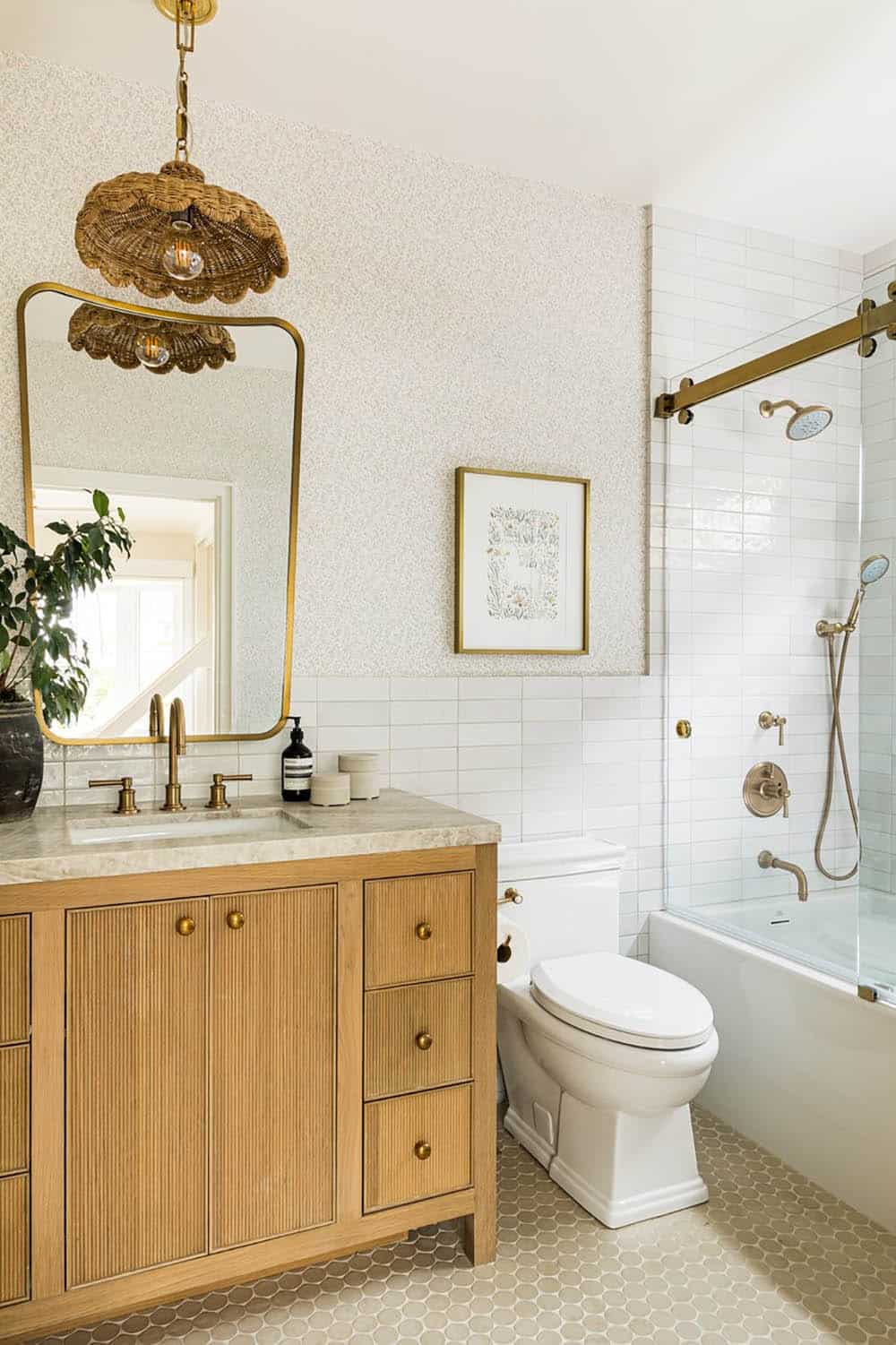 Wallpapered bathroom with scalloped rattan pendant and brass fixtures