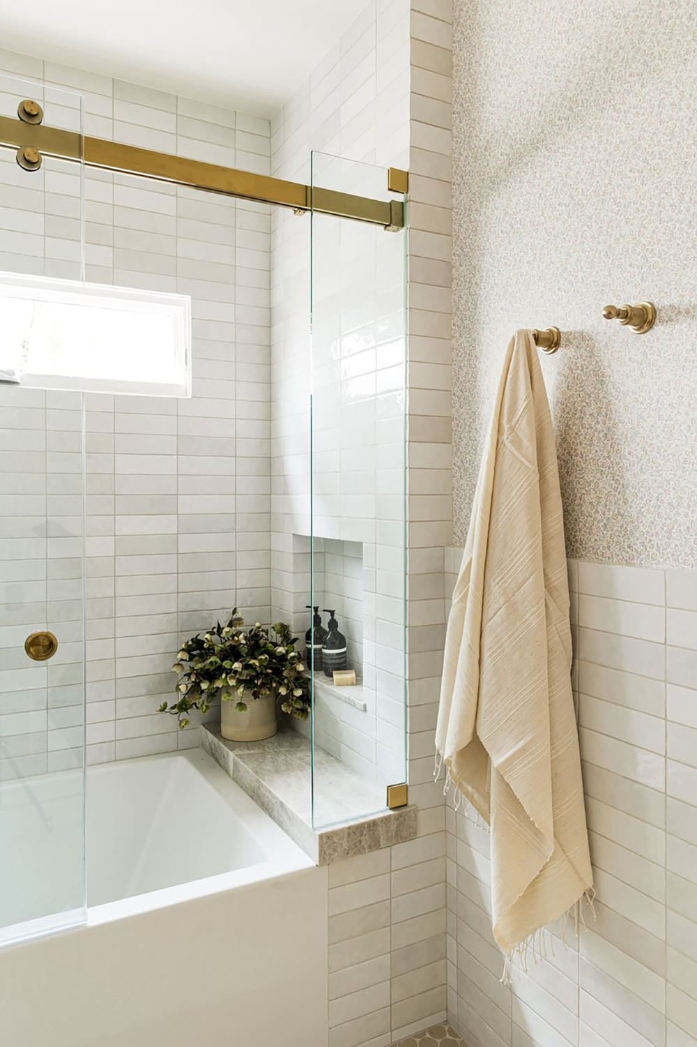 Tiled tub surround with brass hardware and linen towel
