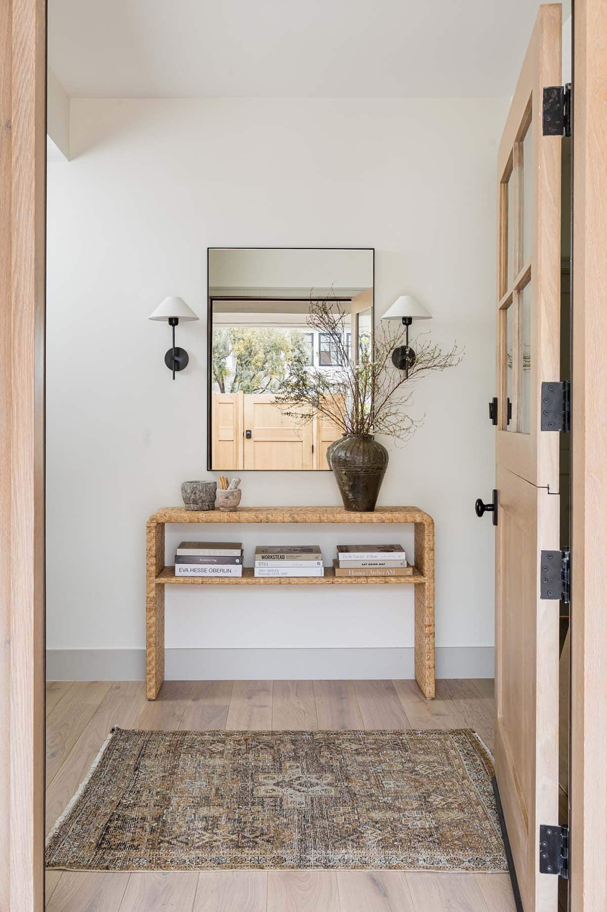 Entryway mirror above woven console table and vintage rug