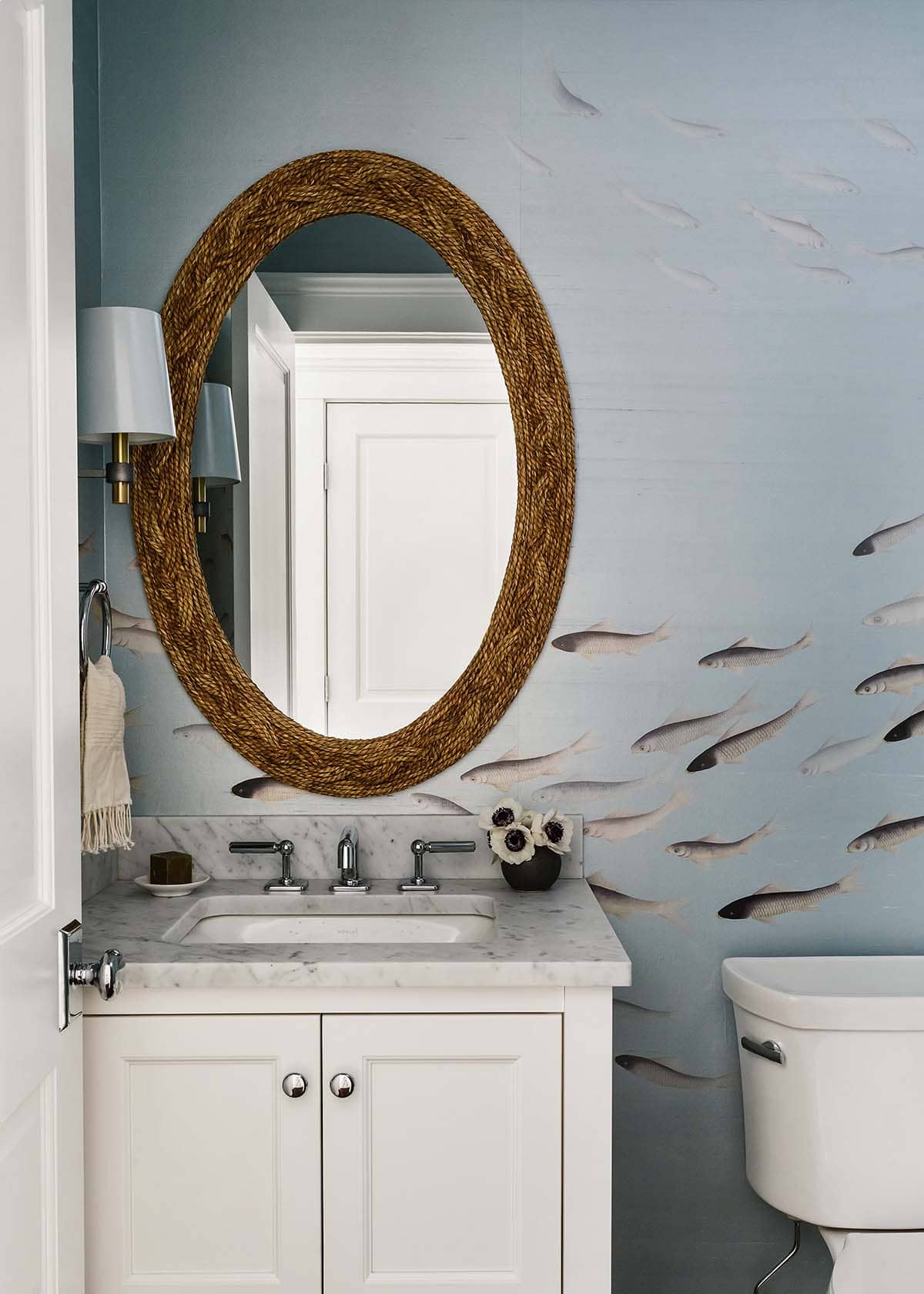 Powder room vanity with woven oval mirror and fish wallpaper