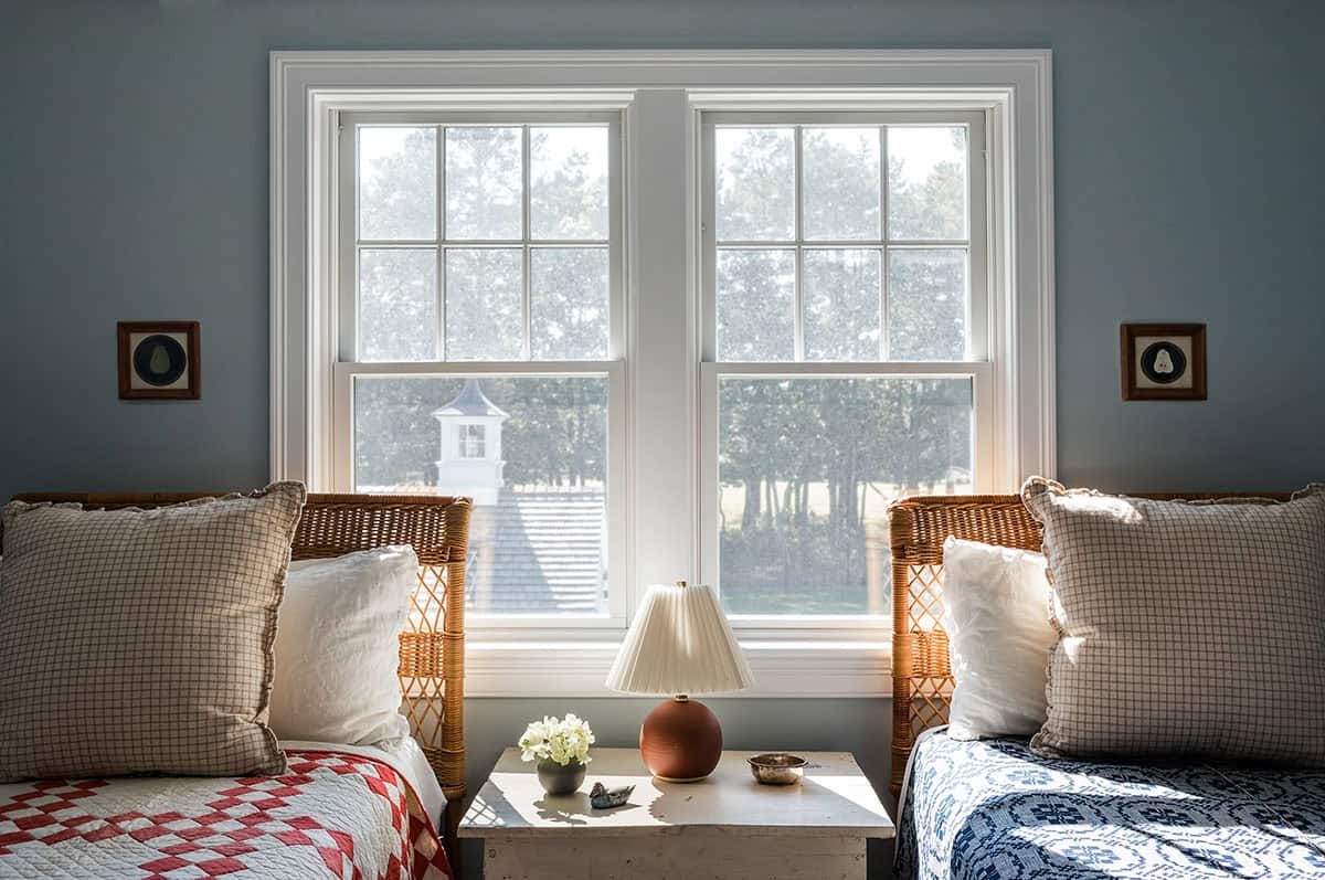 Twin beds with wicker headboards flanking a window nightstand