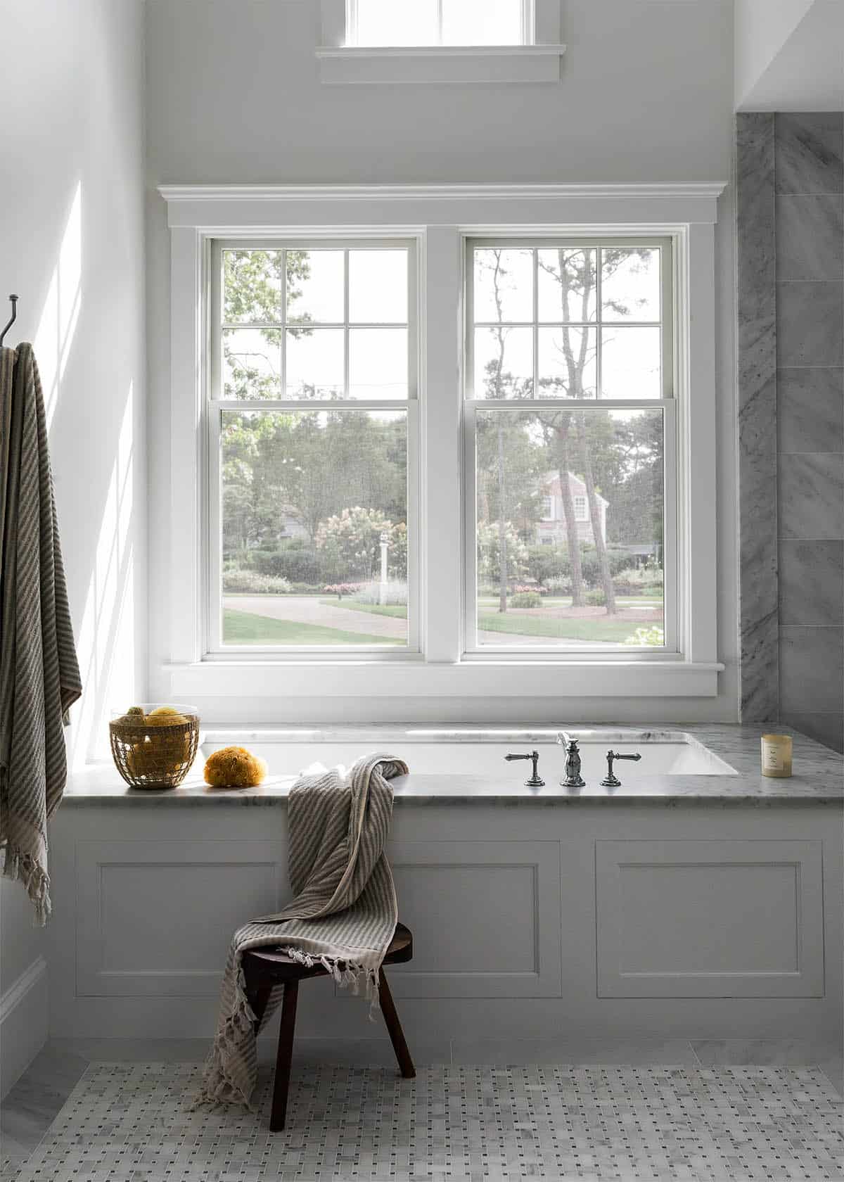Primary bathroom soaking tub with marble surround and garden view