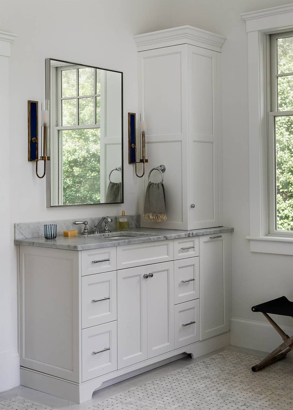 Primary bathroom vanity with marble counter and brass sconces