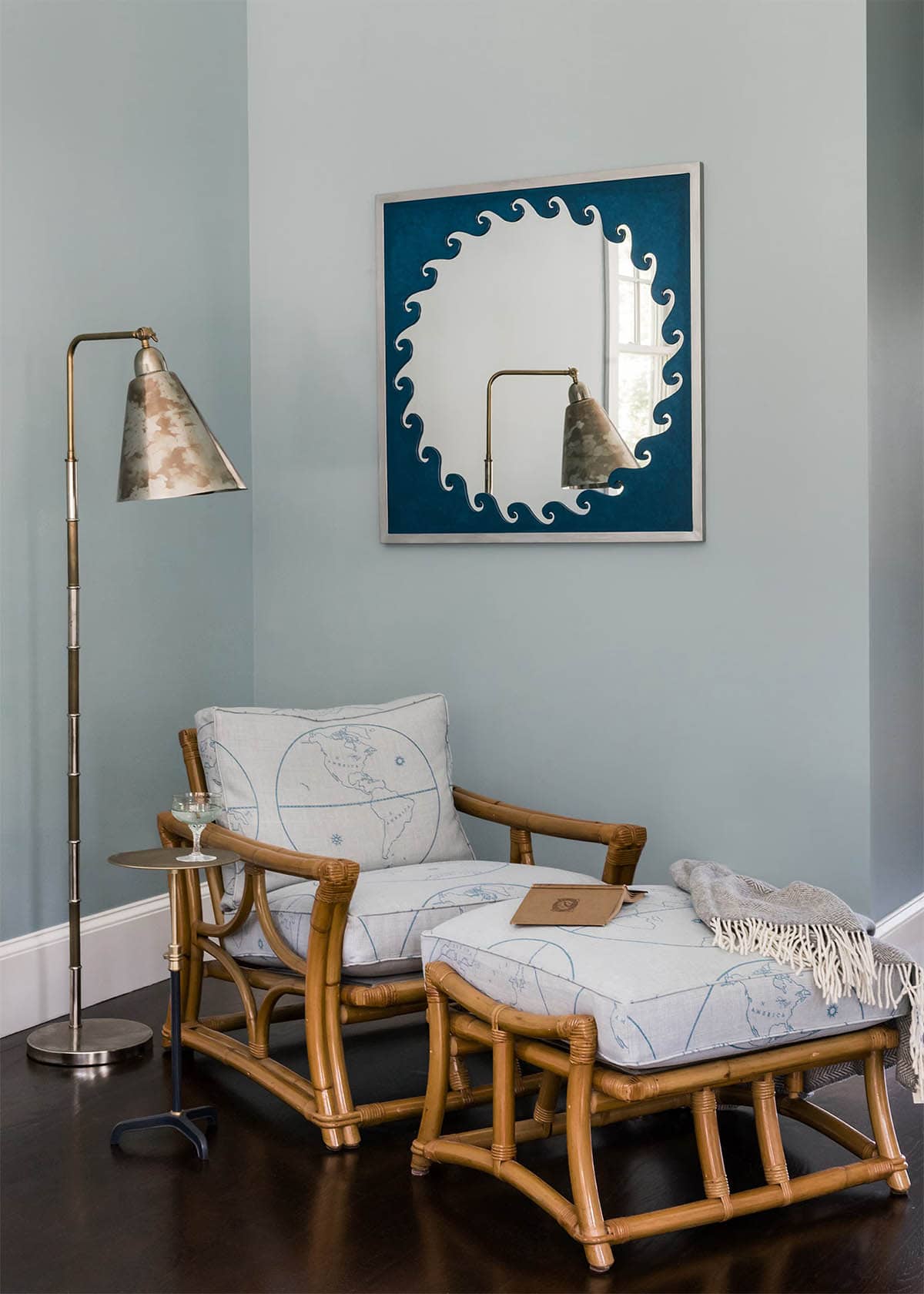 Rattan reading chair and ottoman below a wave motif mirror