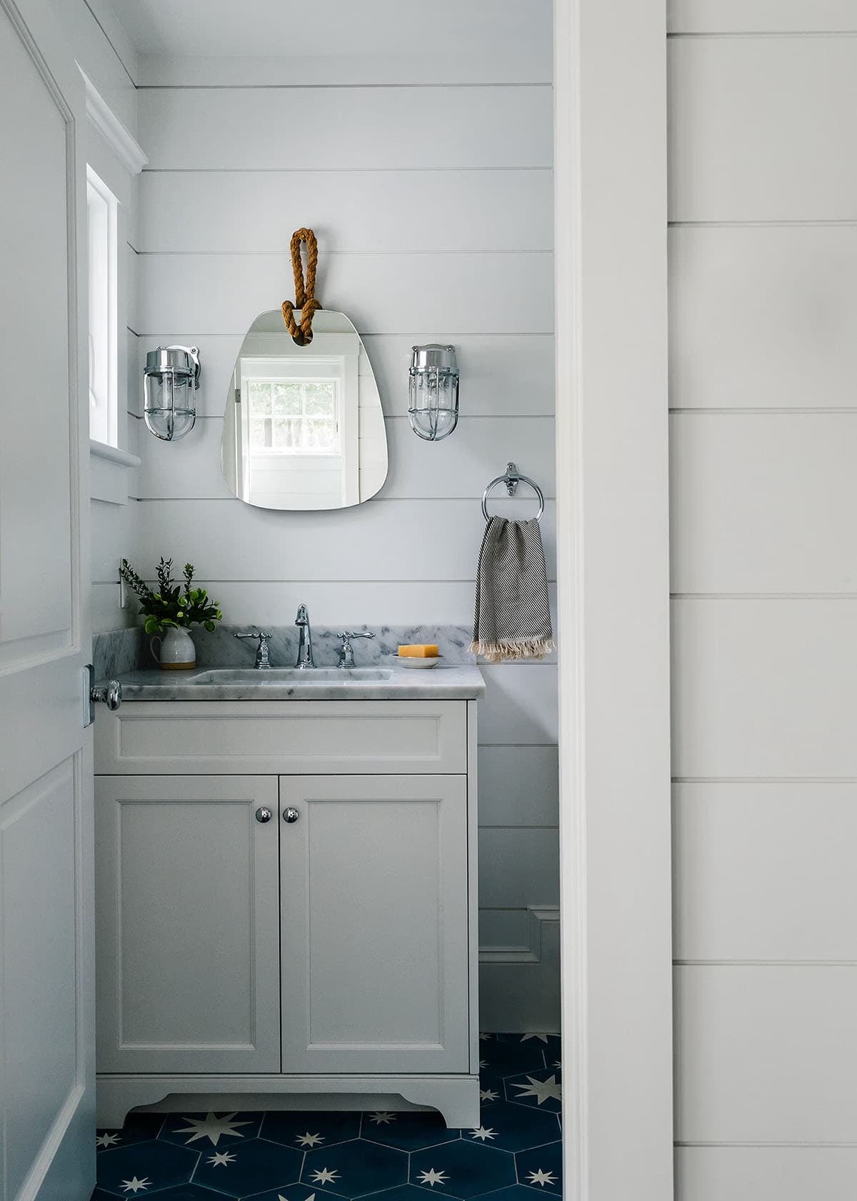Small bathroom with rope hung mirror and star tile floor