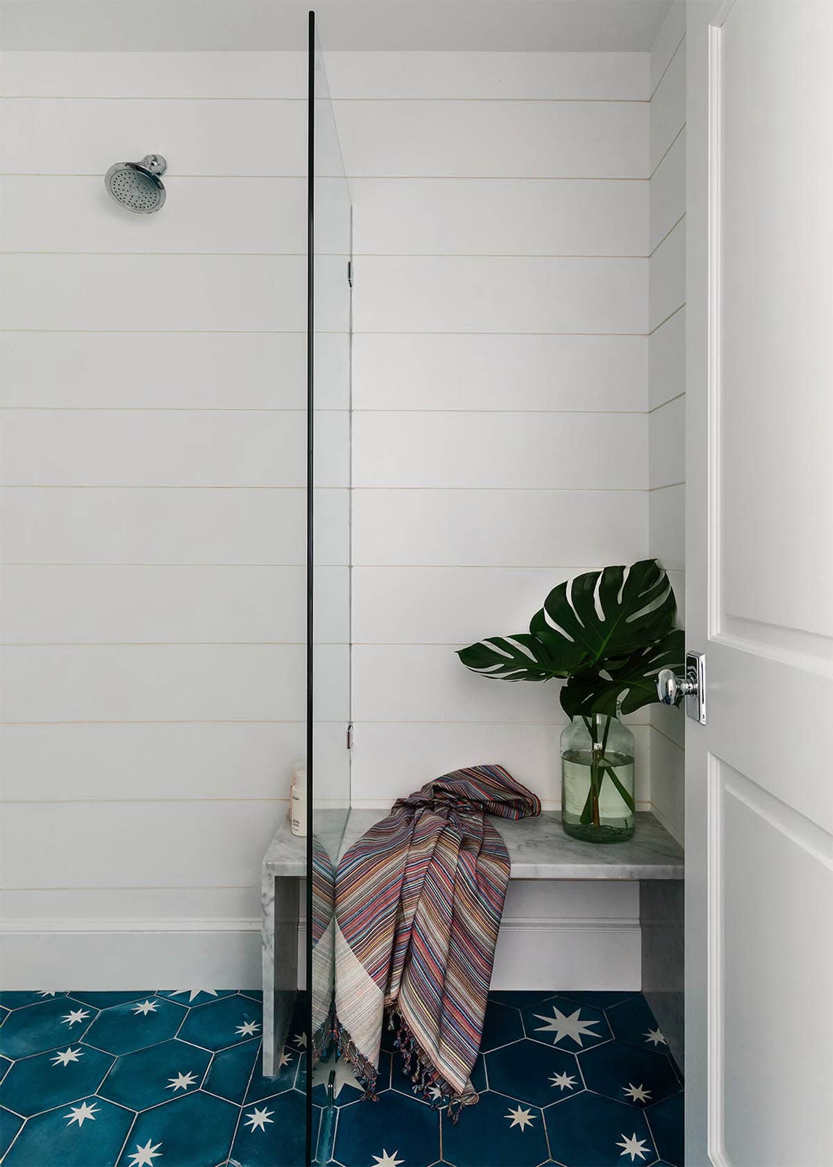 Walk-in shower with star tile floor and marble bench