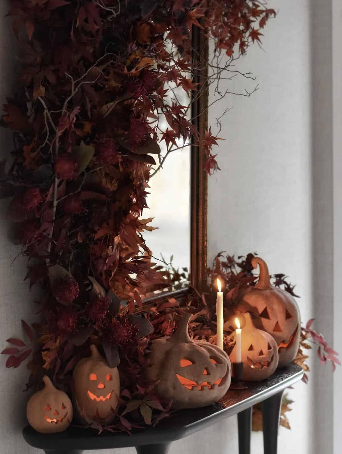 Carved jack-o'-lanterns and taper candles on a console table