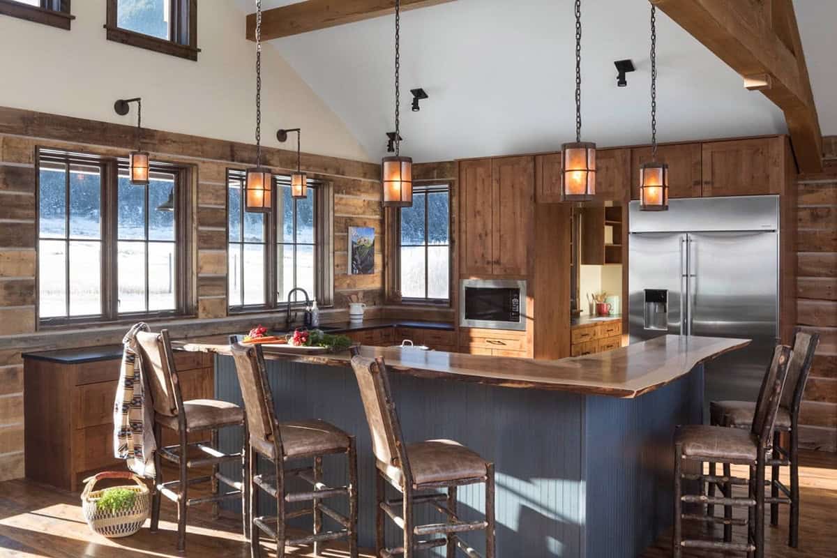 Rustic kitchen with live-edge wood island, blue cabinetry, stainless fridge, and hanging lantern pendant lights