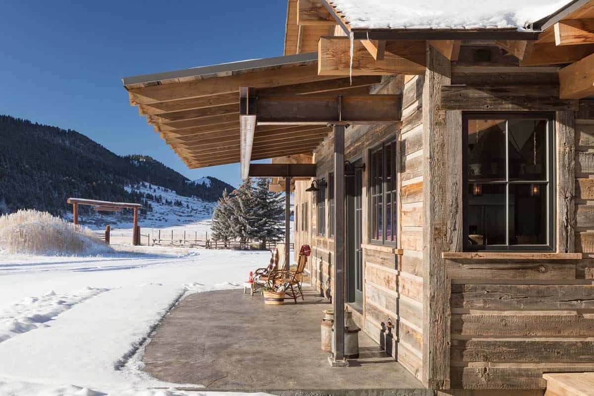 Cabin exterior corner with angled metal roof overhang, mountain and snowy field view