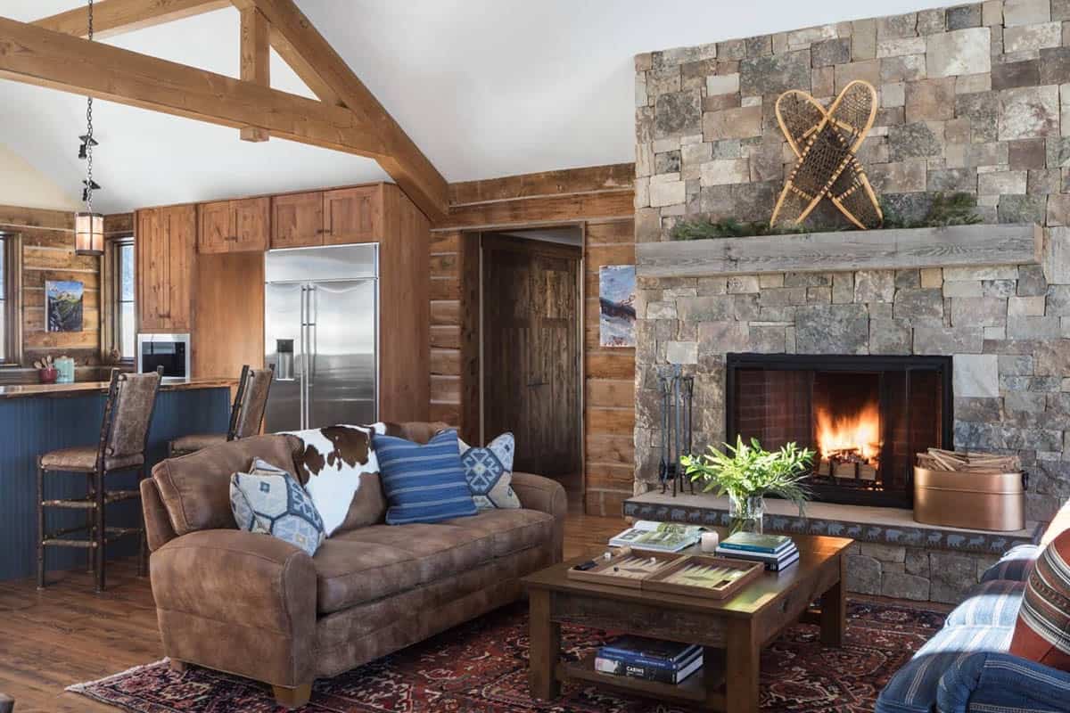 Living room with leather sofa, stone fireplace, and snowshoes mounted above the mantel