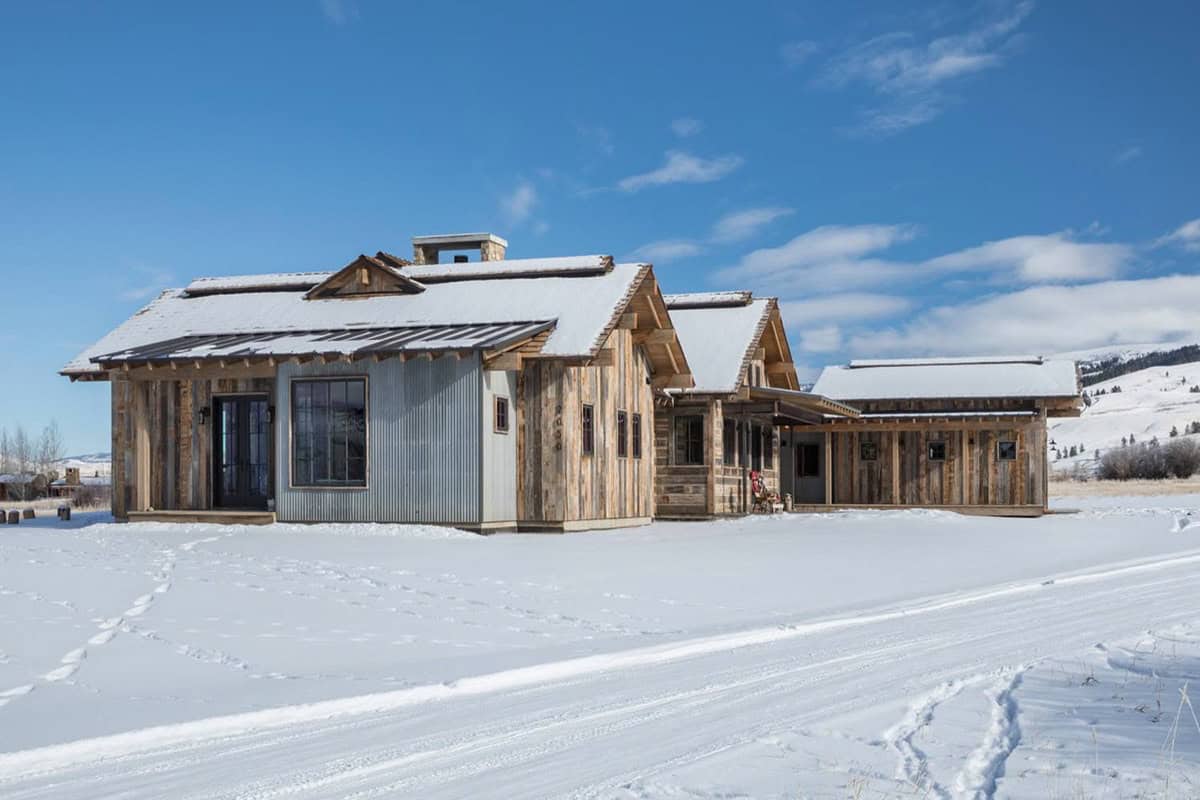 Rustic barnwood house exterior with mixed metal and wood siding under snowy sky