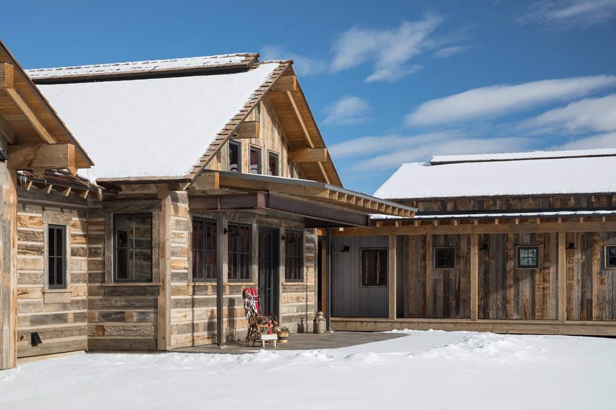 Exterior corner of barnwood cabin with covered walkway connecting two gabled sections