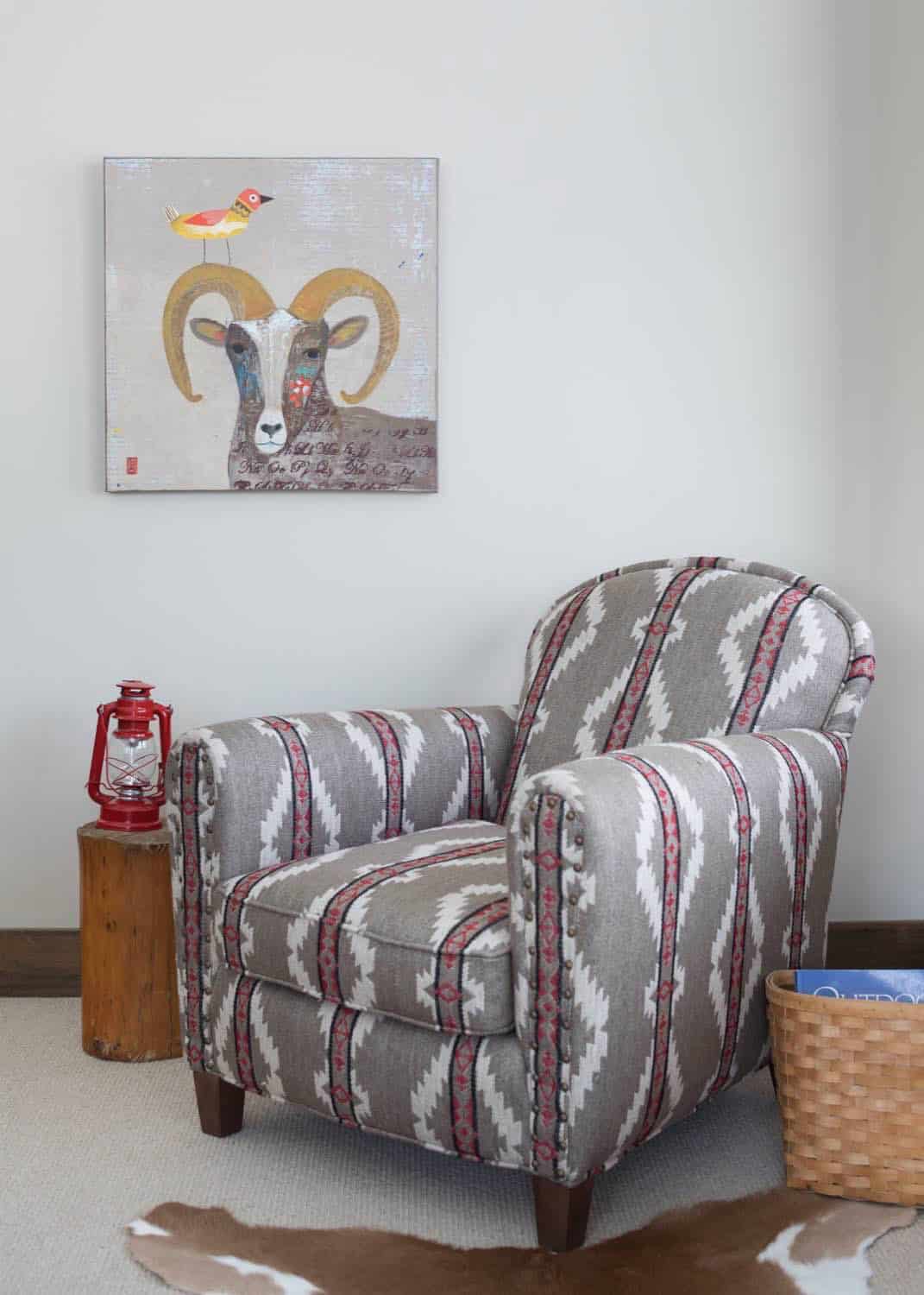 Southwestern-patterned armchair beside a ram-and-bird painting and red lantern on wood stool