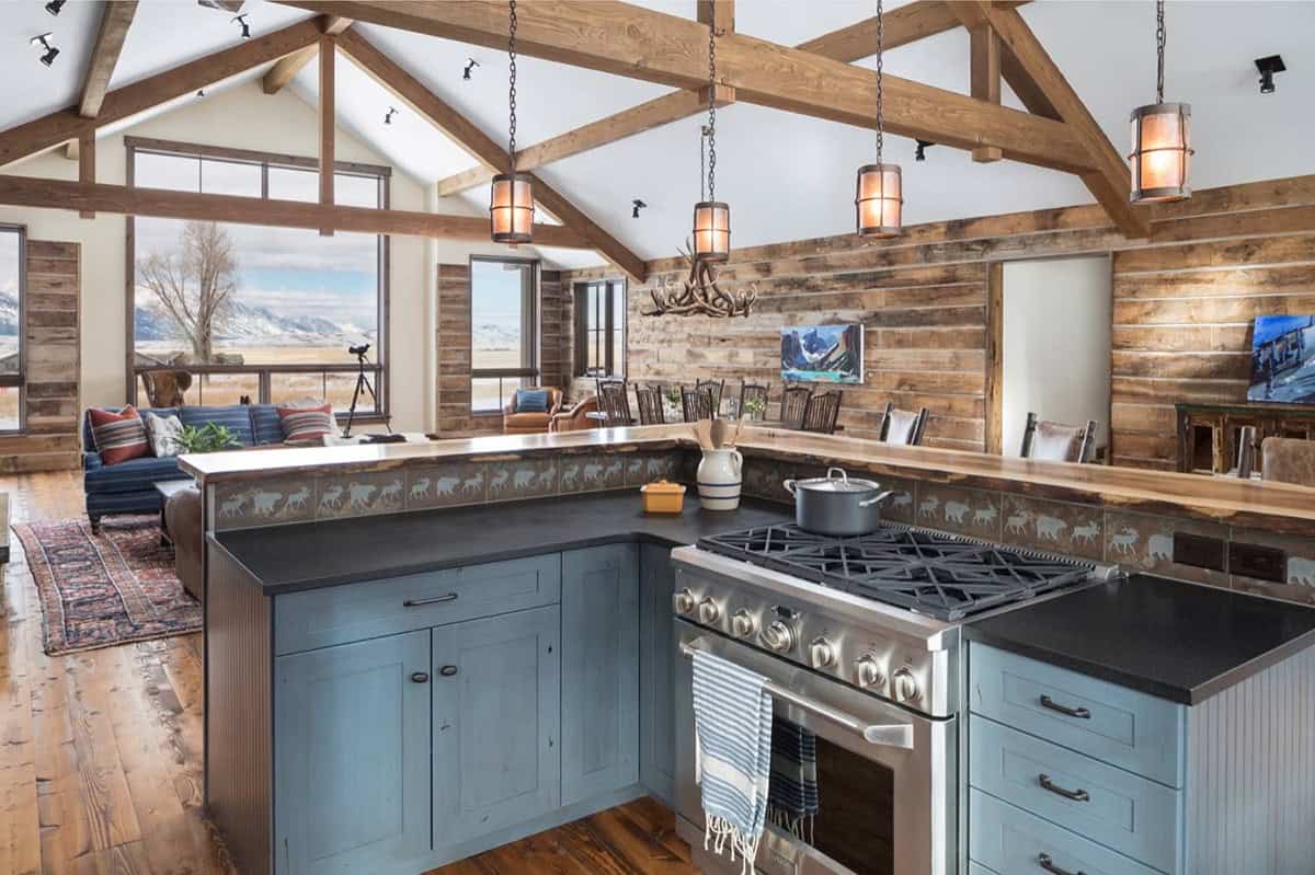 Vaulted-ceiling kitchen and living area with exposed beams, antler chandelier, and mountain view