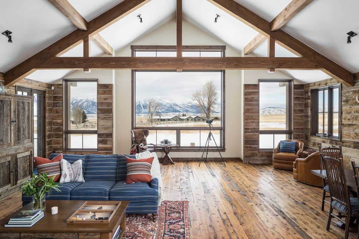 Great room with vaulted wood-beam ceiling, blue striped sofa, and large mountain-view window