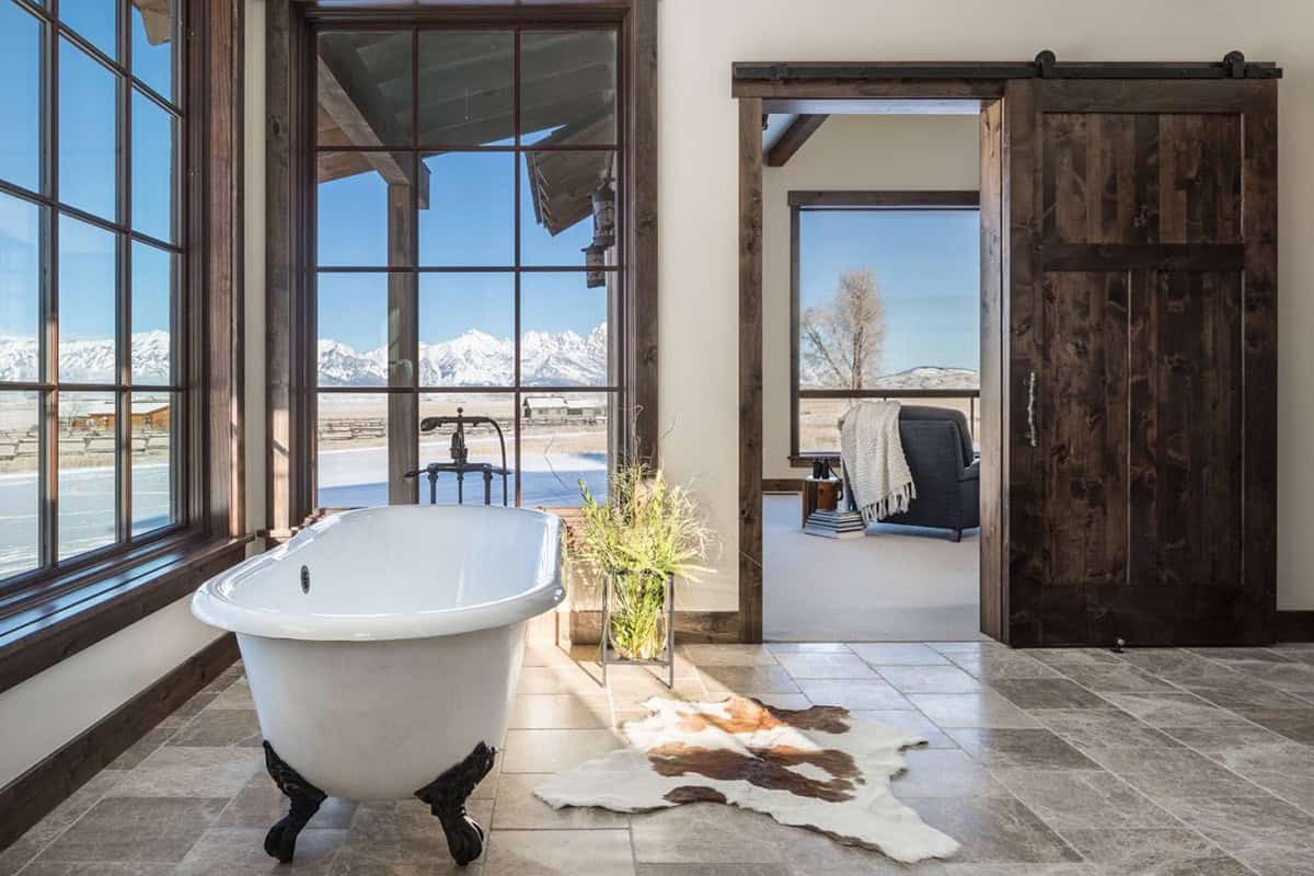 Bathroom with clawfoot tub, mountain-view windows, and sliding barn door to bedroom