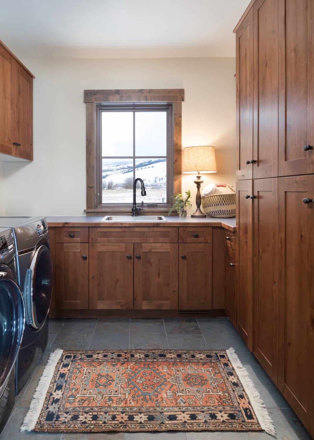 Laundry room with dark wood cabinetry, front-load washer and dryer, and patterned rug