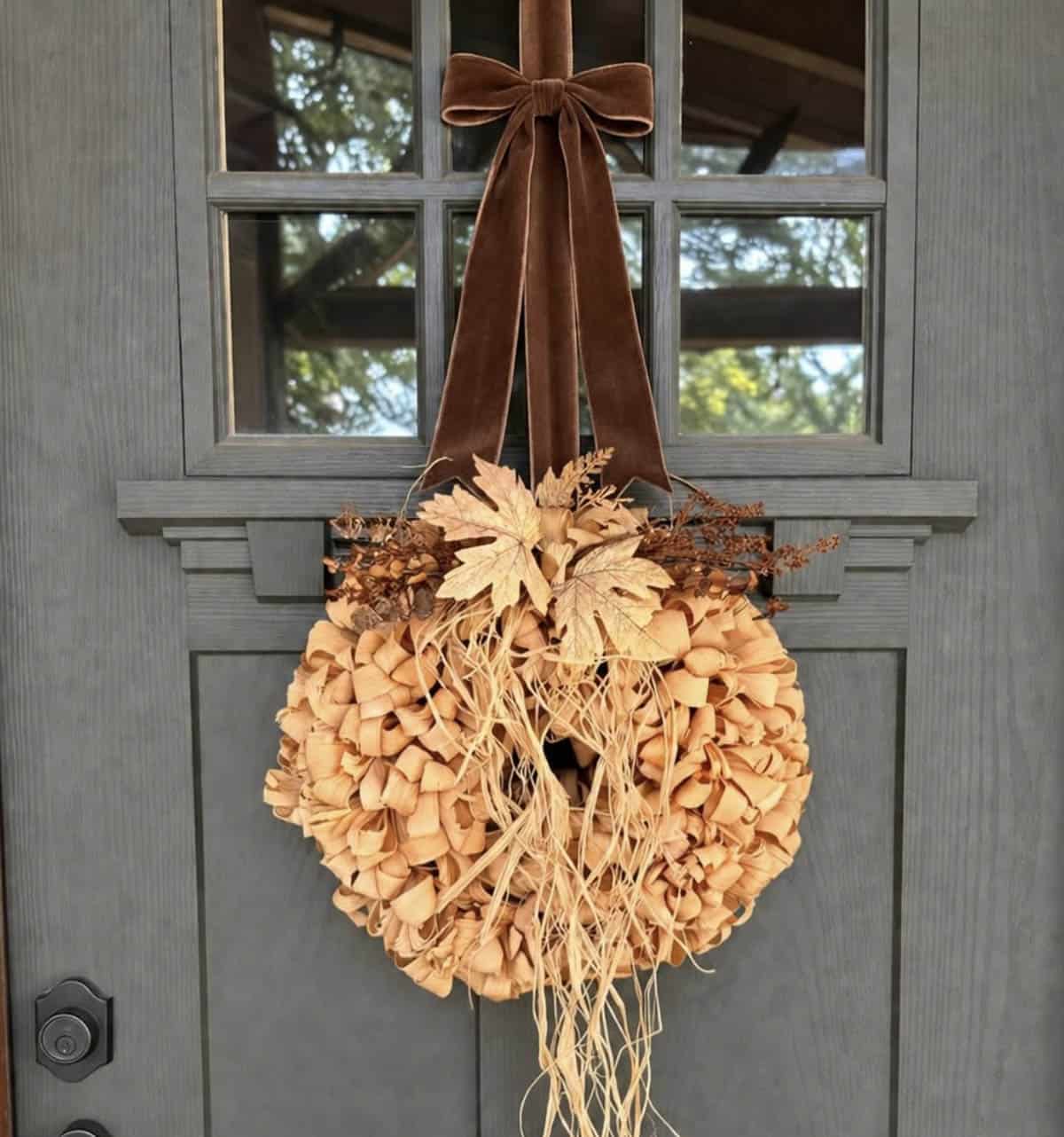 Corn husk wreath with dried florals and velvet bow on gray front door