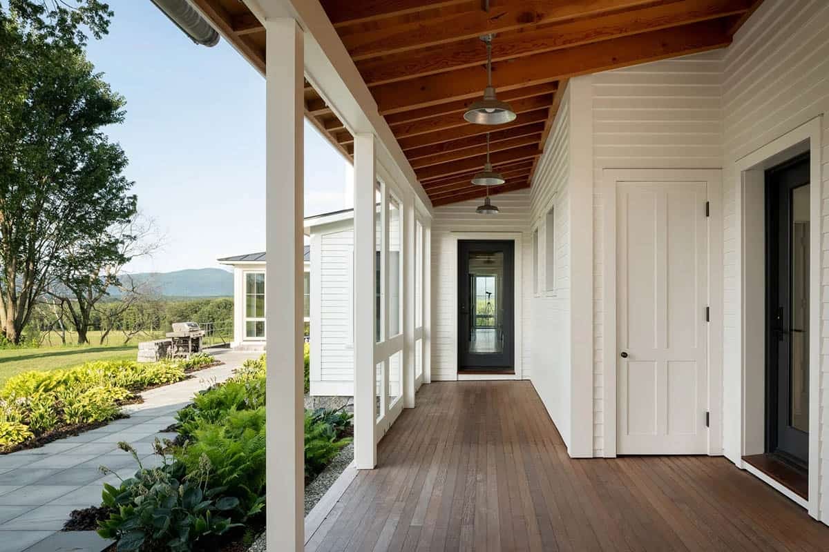 Covered porch with wood plank floor, exposed timber ceiling, and barn pendant lights