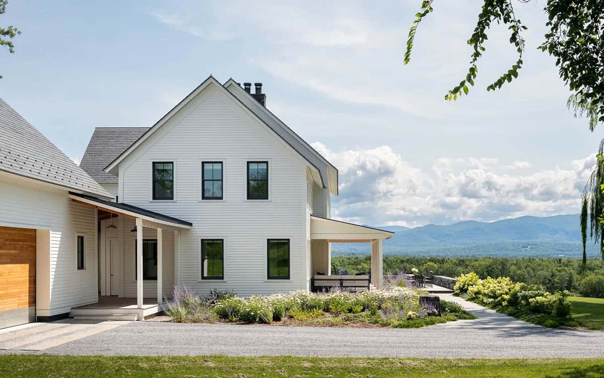 Side of the farmhouse with covered porch and terrace overlooking the Green Mountains
