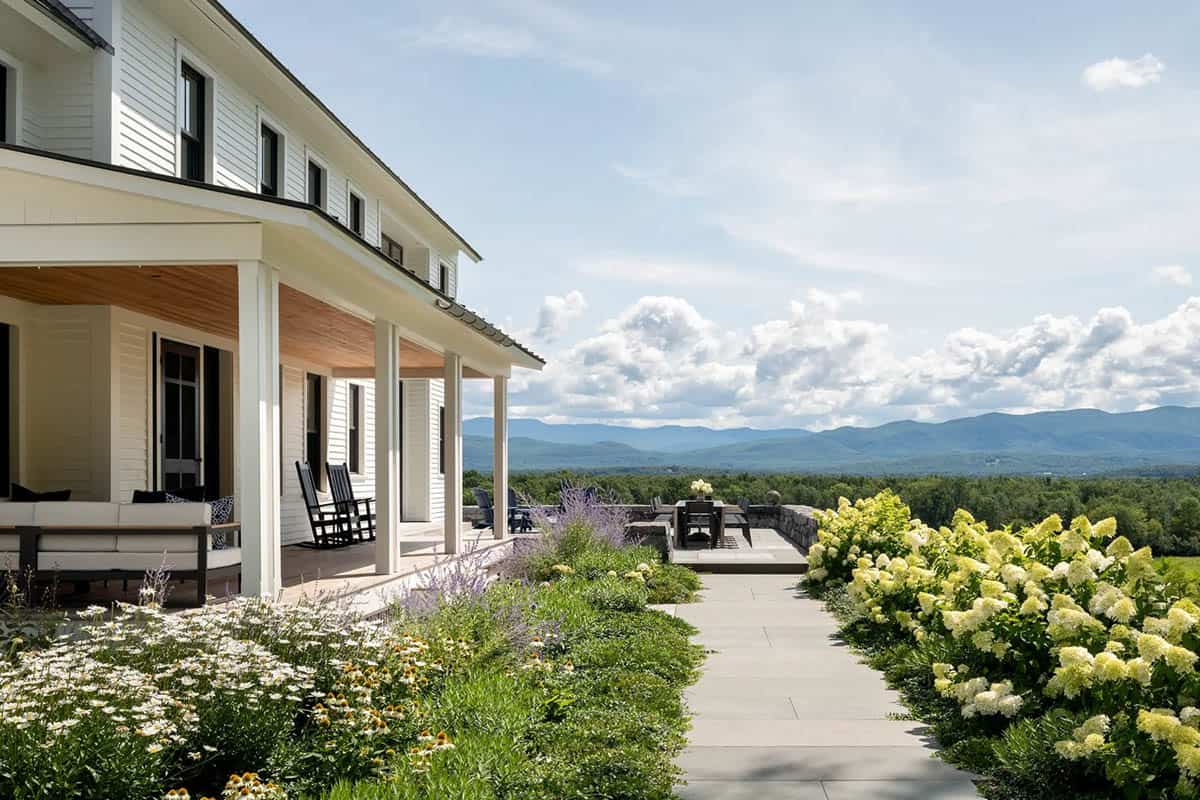 Covered porch with rocking chairs and bluestone path leading to a mountain-view terrace