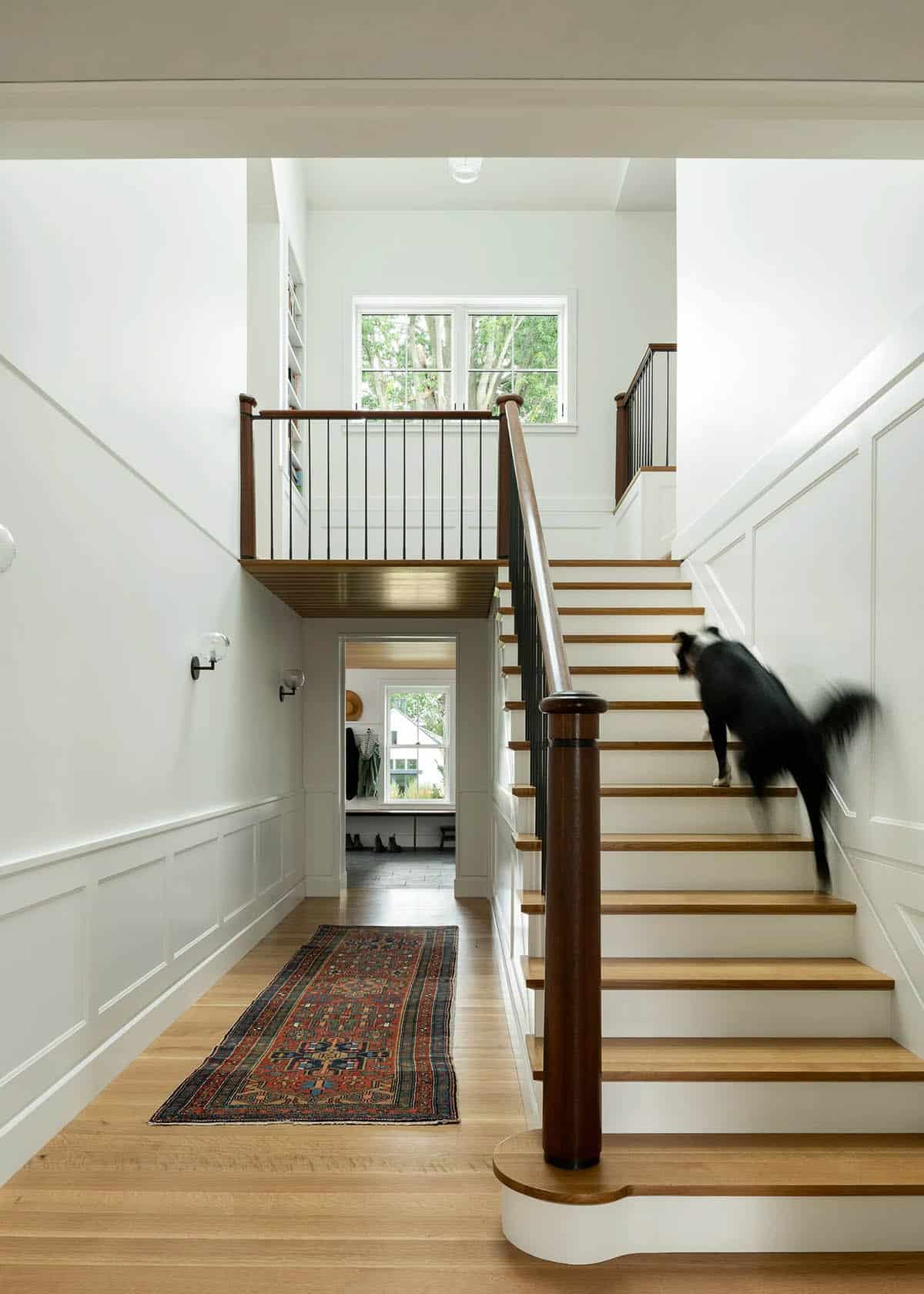 Entry stair with mahogany handrail, steel balusters, white oak treads, and paneled walls
