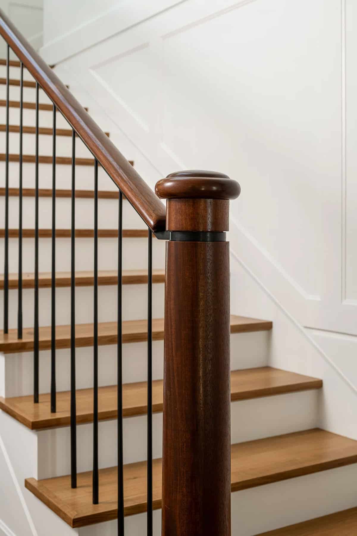 Close-up of mahogany newel post with steel balusters and white oak stair treads