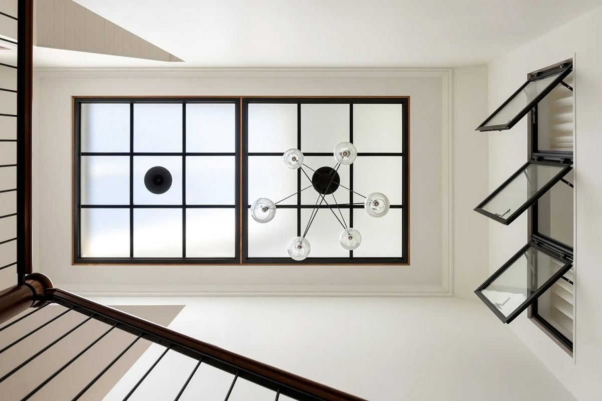 Looking up at stairwell skylight, glass globe chandelier, and operable steel-framed windows