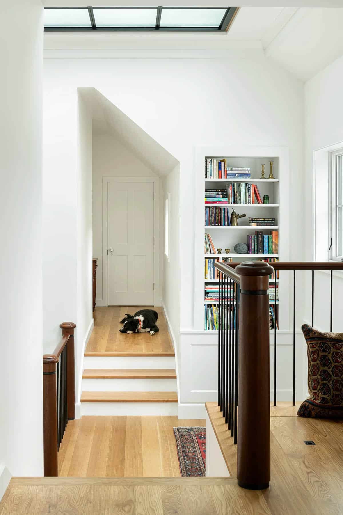Upper landing with built-in bookcase, mahogany railing, and skylight
