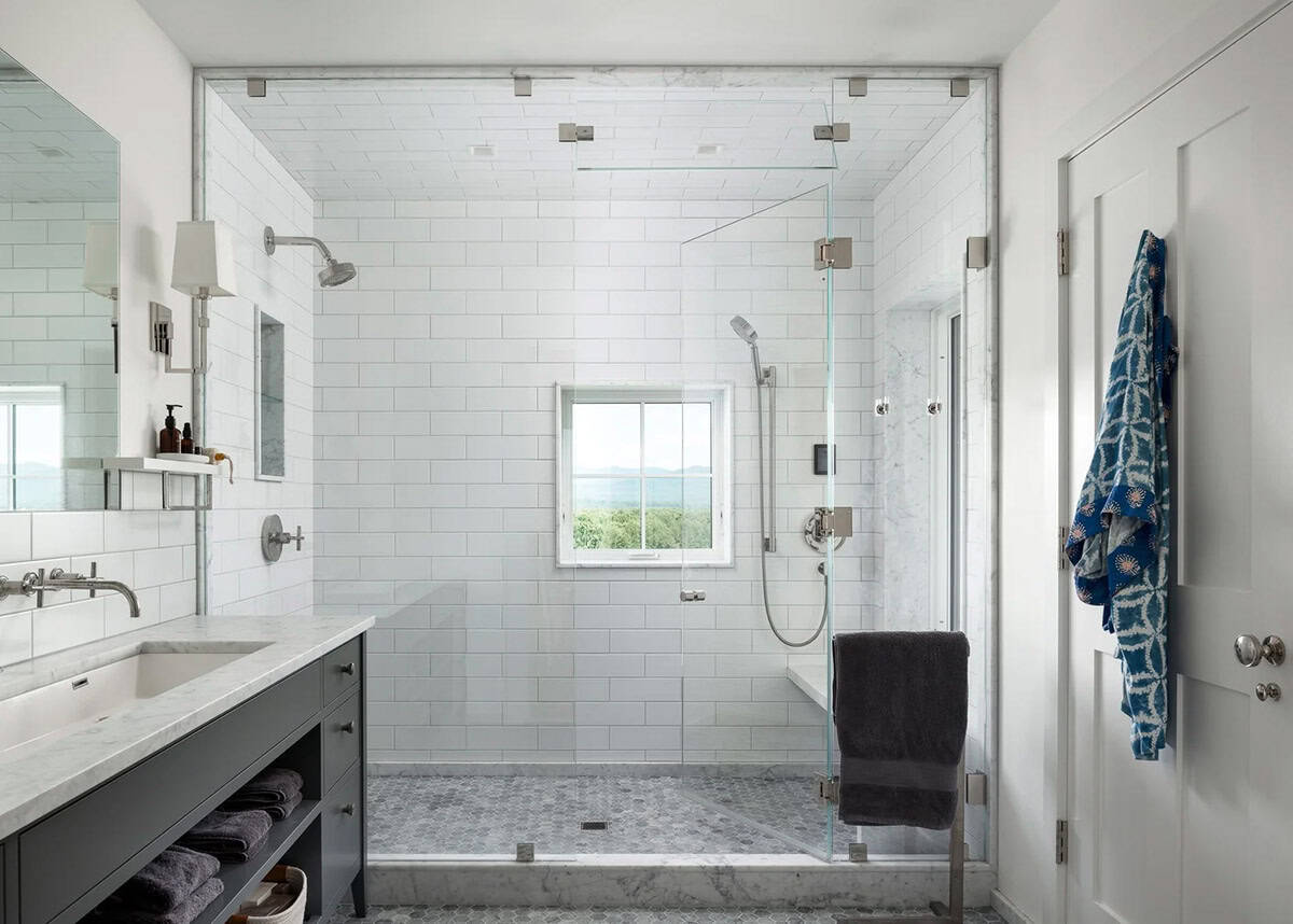 Primary bathroom with glass-enclosed walk-in shower, white subway tile, and marble accents