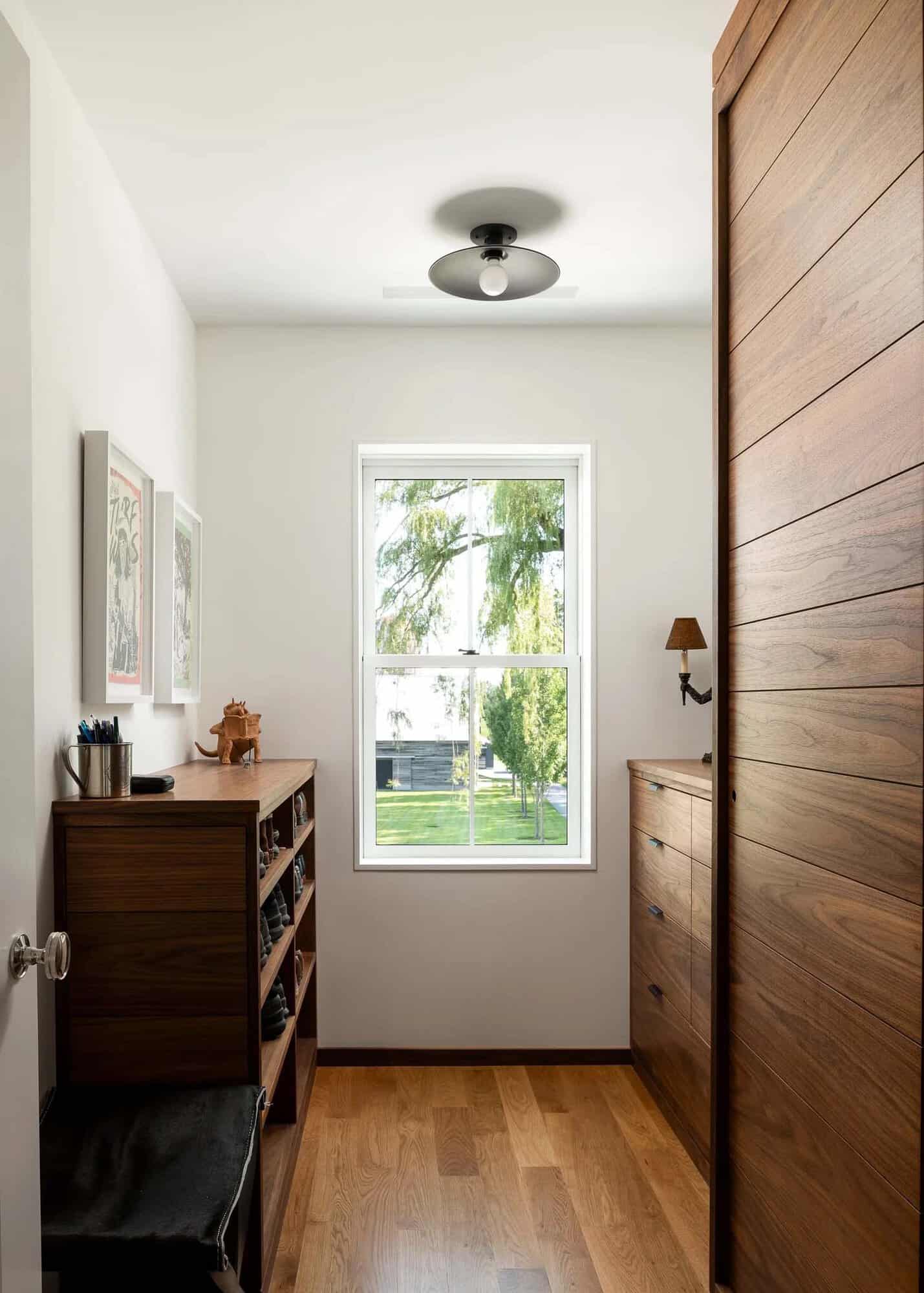 Walnut dressing room with custom built-in drawers, shoe storage, and sliding wardrobe door
