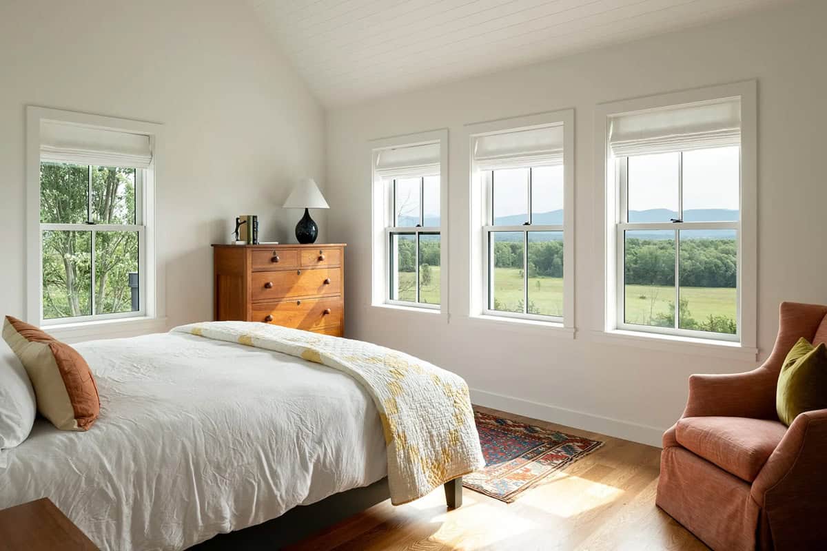 Bedroom with vaulted shiplap ceiling and three windows framing Green Mountain views