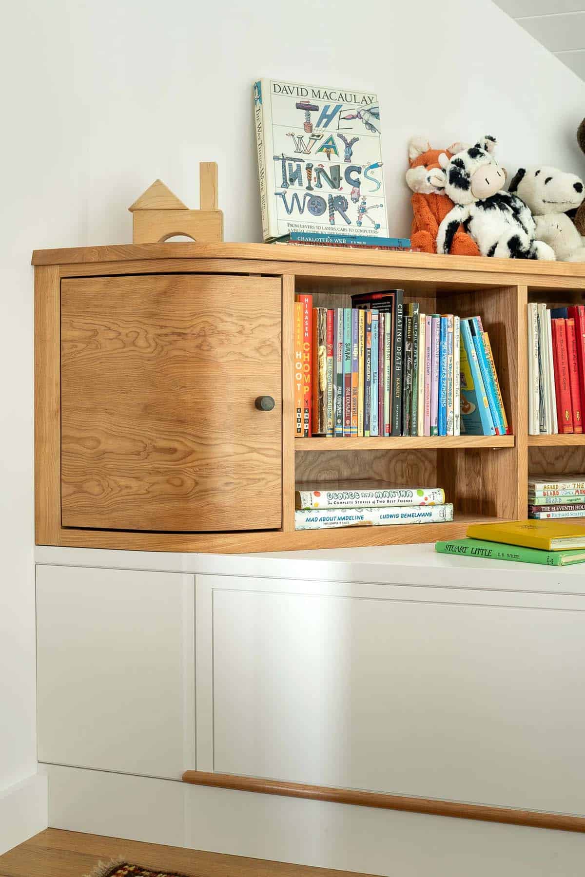 Custom built-in bookshelf with curved cabinet door above white storage drawers