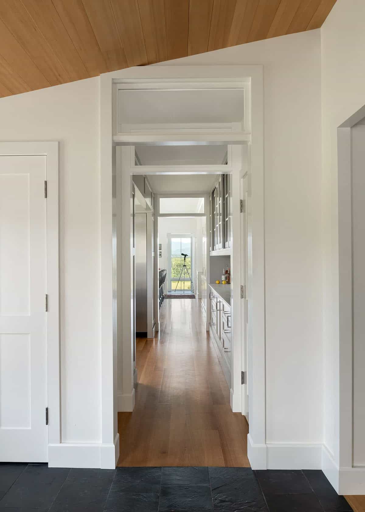 Hallway with slate floor and transom windows leading toward the kitchen and mountain view