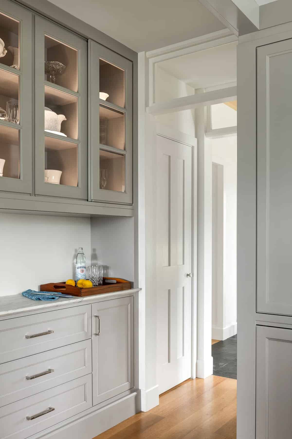 Butler's pantry with gray glass-front cabinets, marble counter, and brushed nickel hardware
