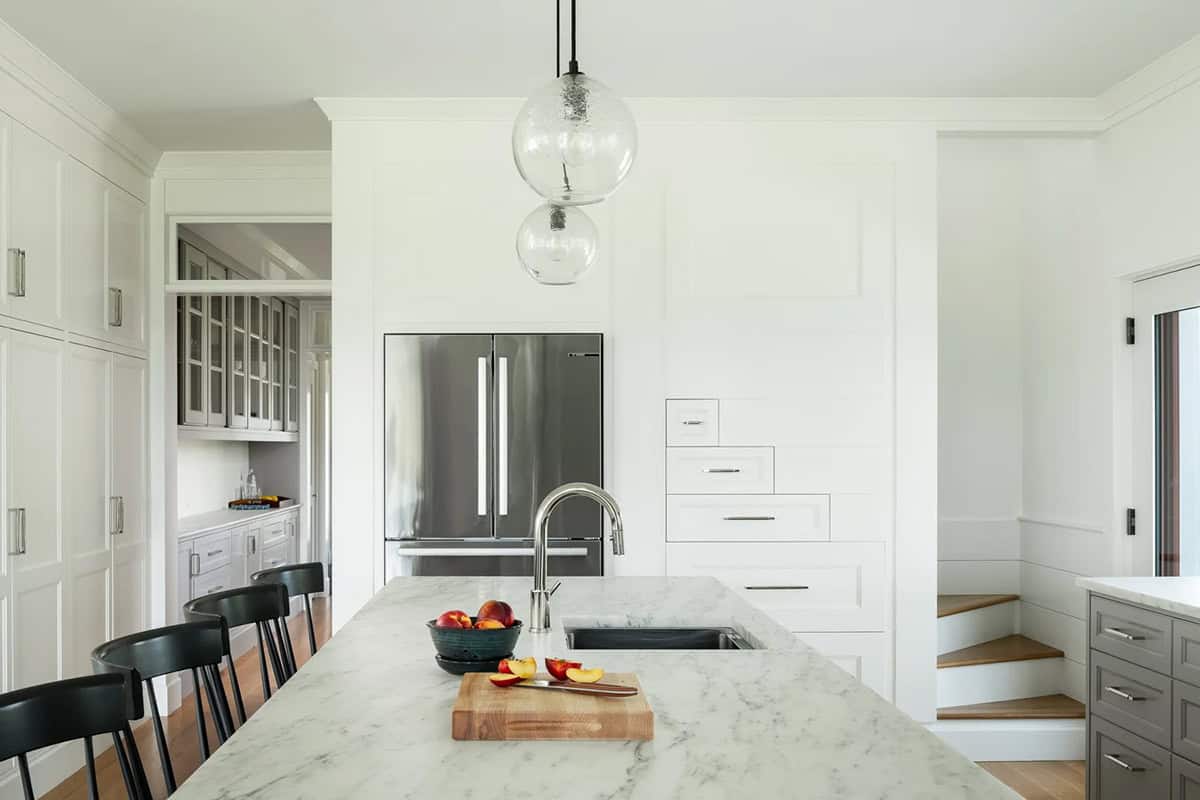 Kitchen island with marble countertop, glass pendants, stainless refrigerator, and built-in drawers
