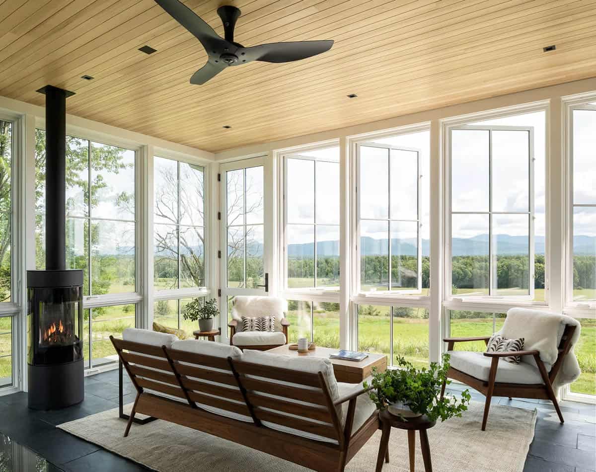 Sunroom lounge with modern stove, walnut sofa, and wide mountain views