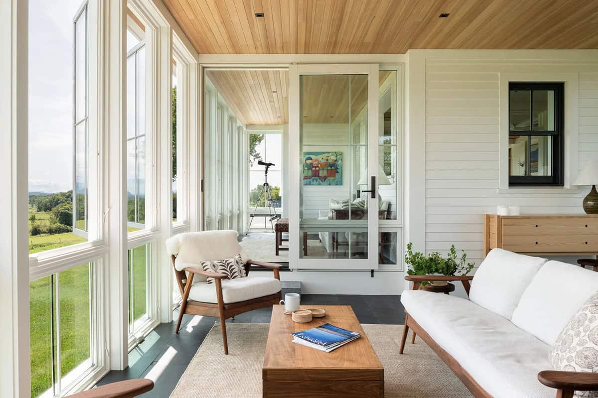 Sunroom with walnut coffee table, sheepskin-draped lounge chair, and glass door to the adjoining room