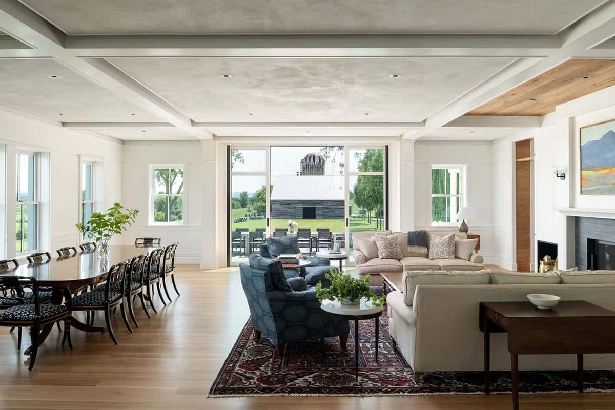 Open living and dining area with coffered ceiling, long dining table, and sliding doors to the patio